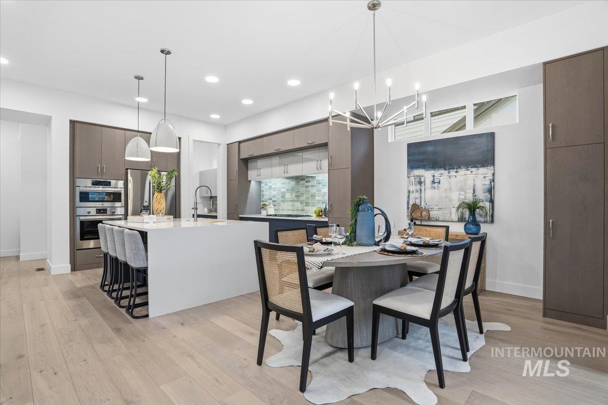 Dining space with light wood-style flooring, a chandelier, and recessed lighting