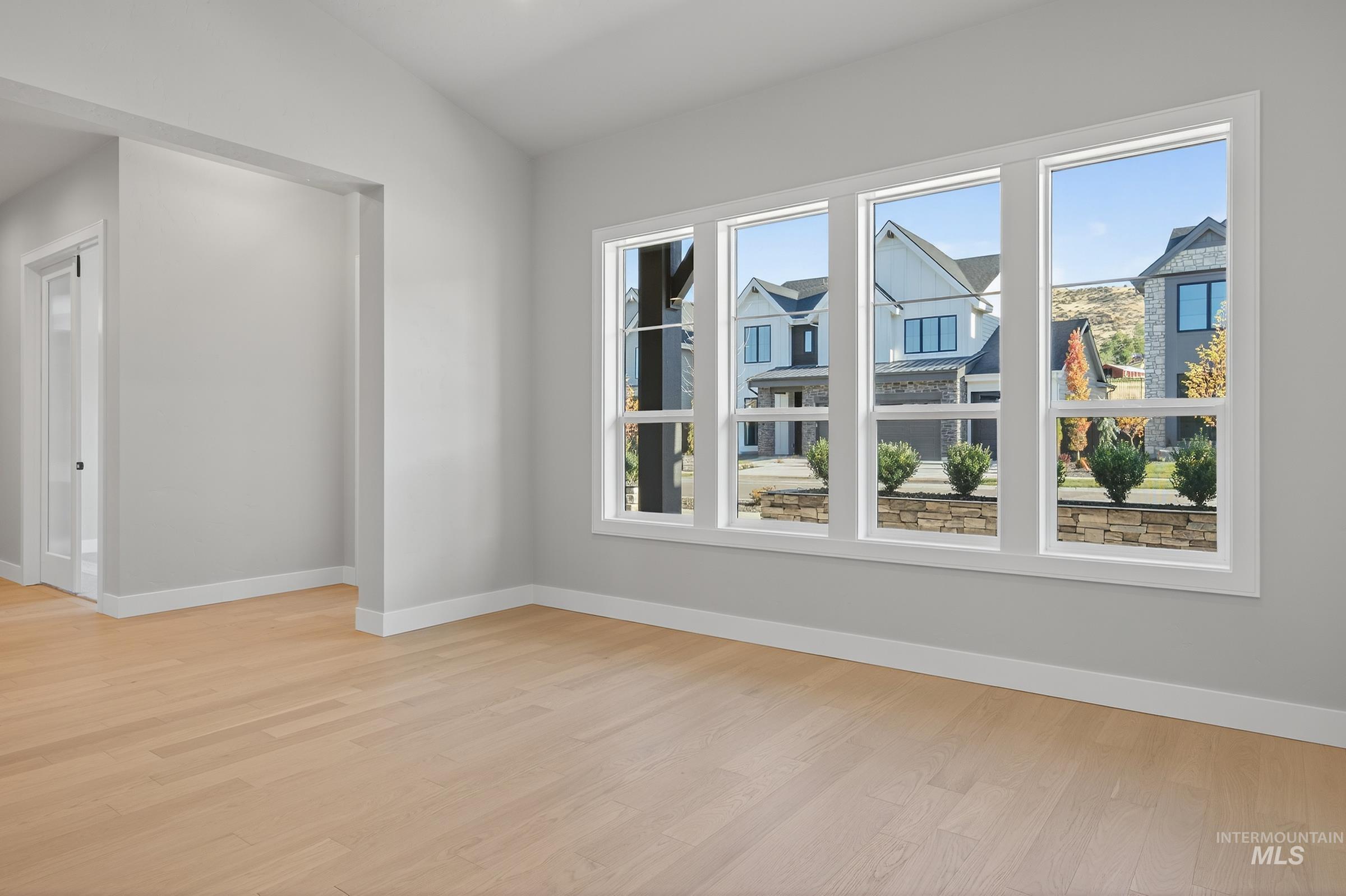 Empty room with healthy amount of natural light, light wood-style floors, and lofted ceiling