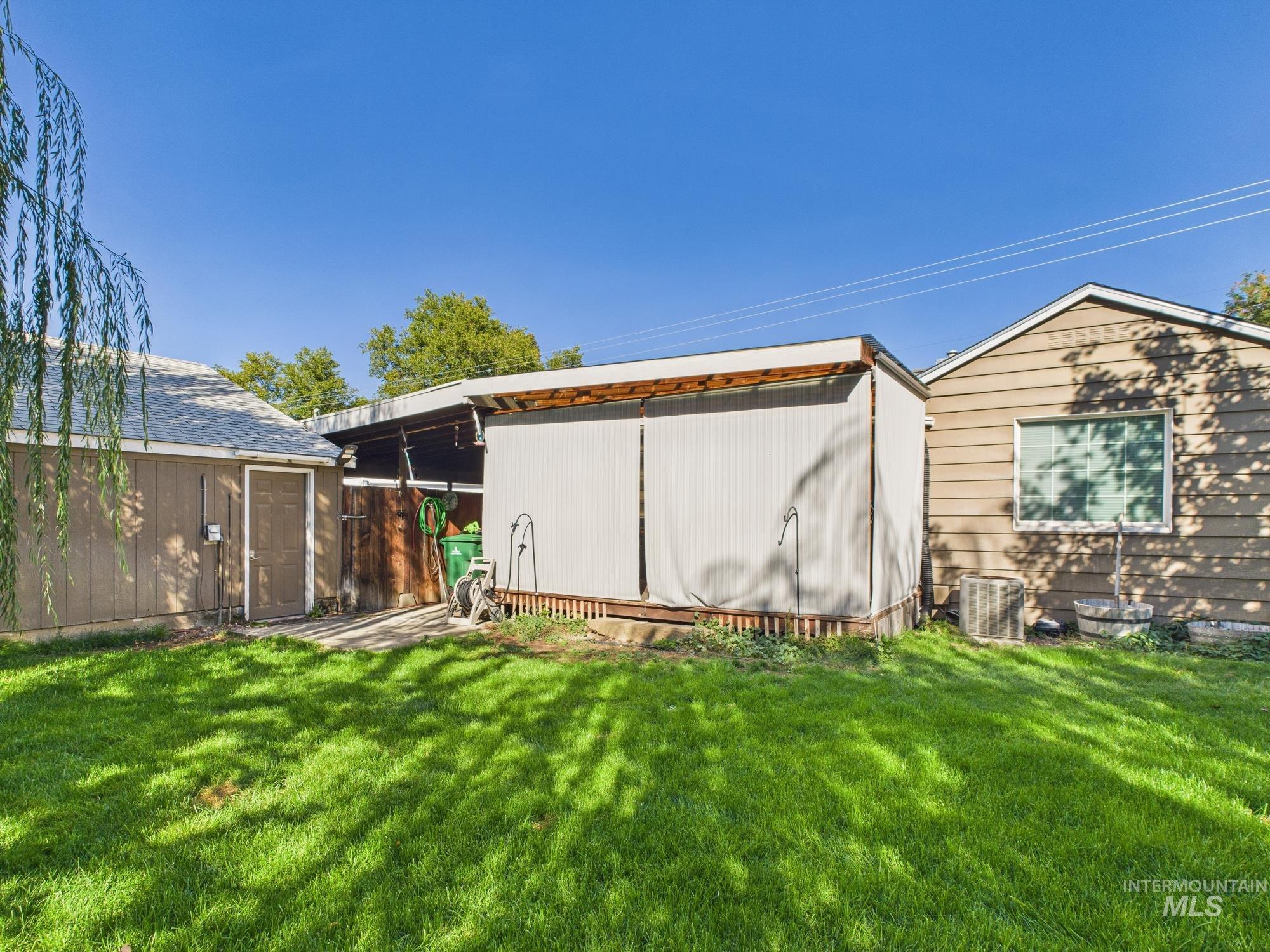 View of property exterior with a lawn and a shed