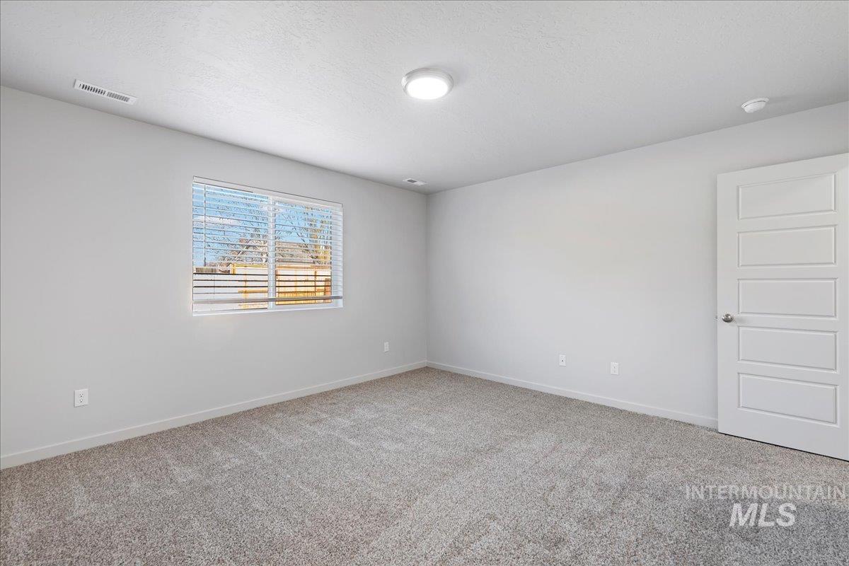 Unfurnished room featuring light carpet and a textured ceiling