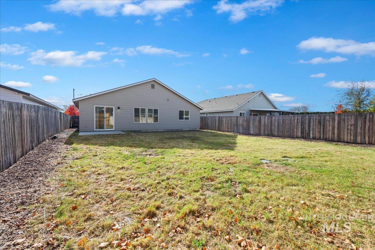 Back of house with a fenced backyard and a patio