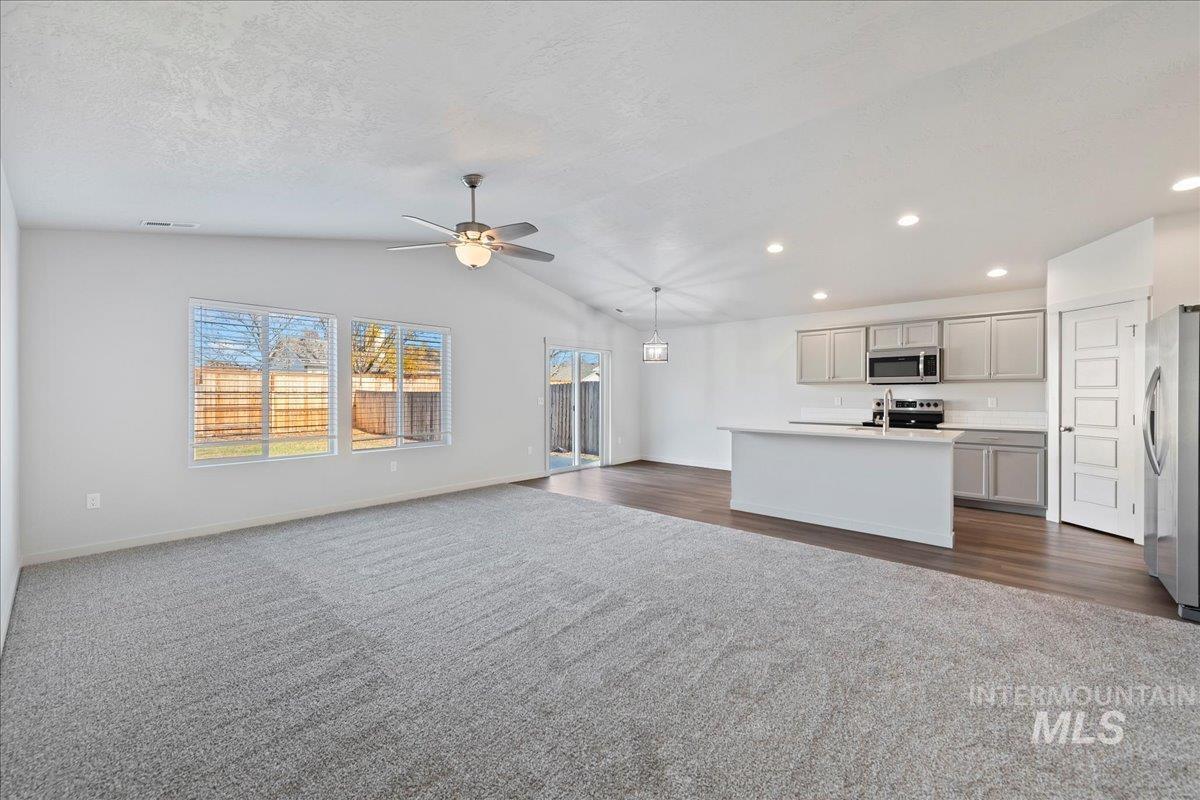 Unfurnished living room featuring lofted ceiling, a ceiling fan, dark carpet, and recessed lighting