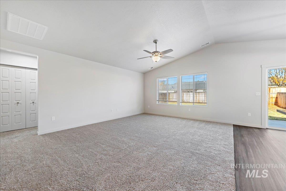 Empty room featuring vaulted ceiling, carpet floors, ceiling fan, and a textured ceiling