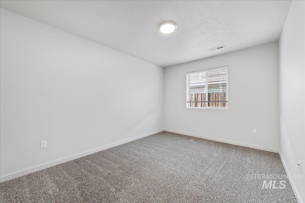 Carpeted spare room featuring baseboards and a textured ceiling