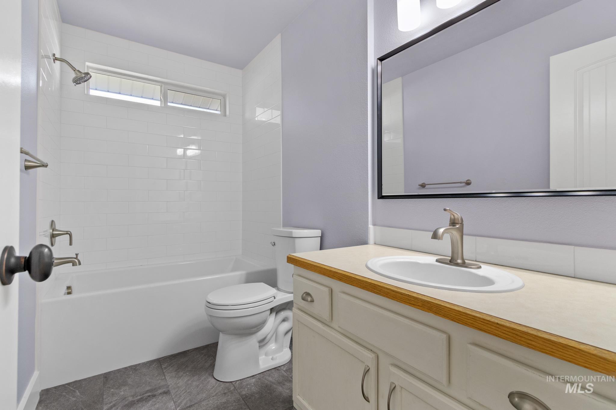 Full bathroom with  shower combination, vanity, and dark tile patterned flooring