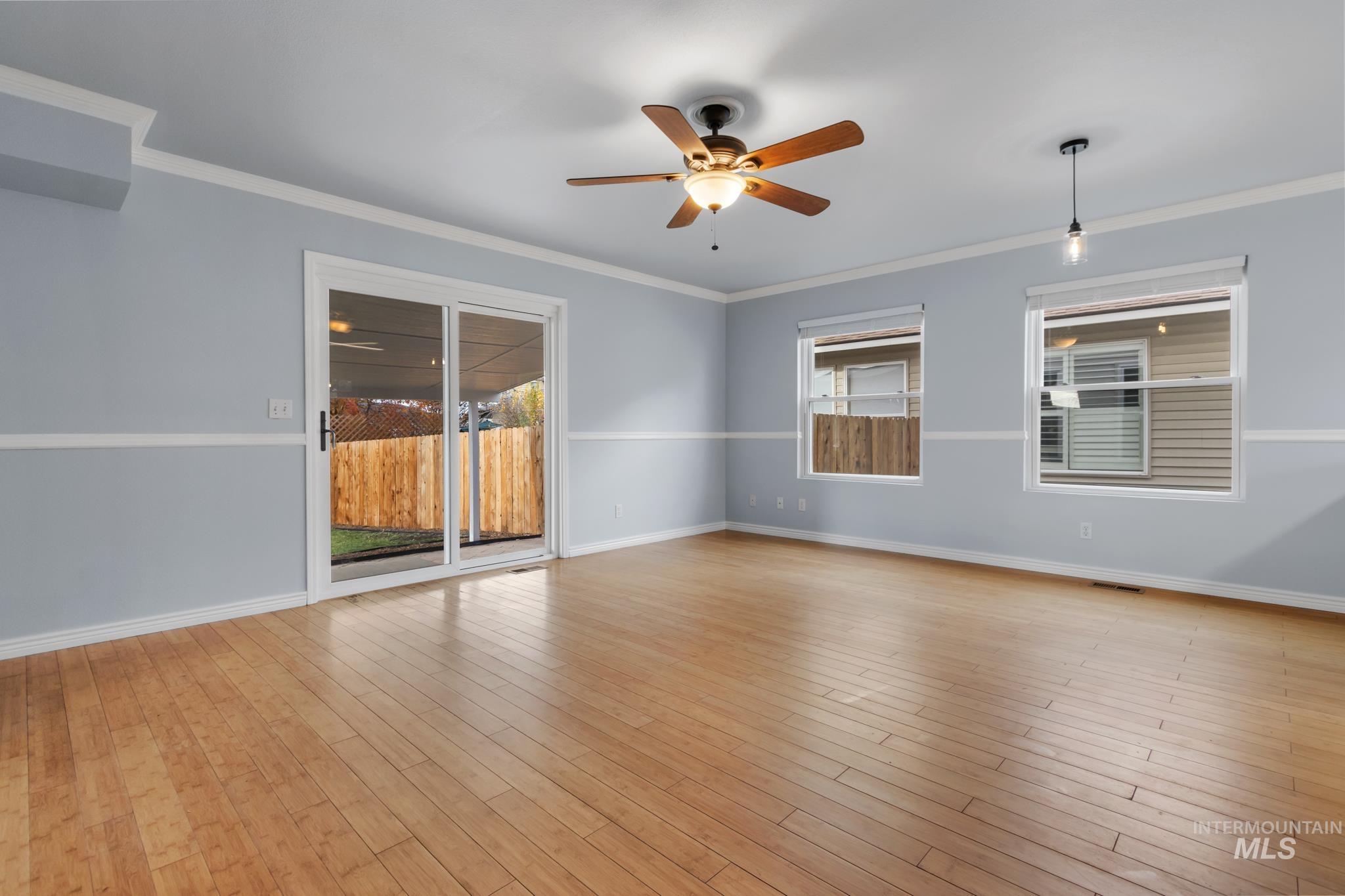 Empty room featuring ceiling fan, light wood finished floors, and ornamental molding