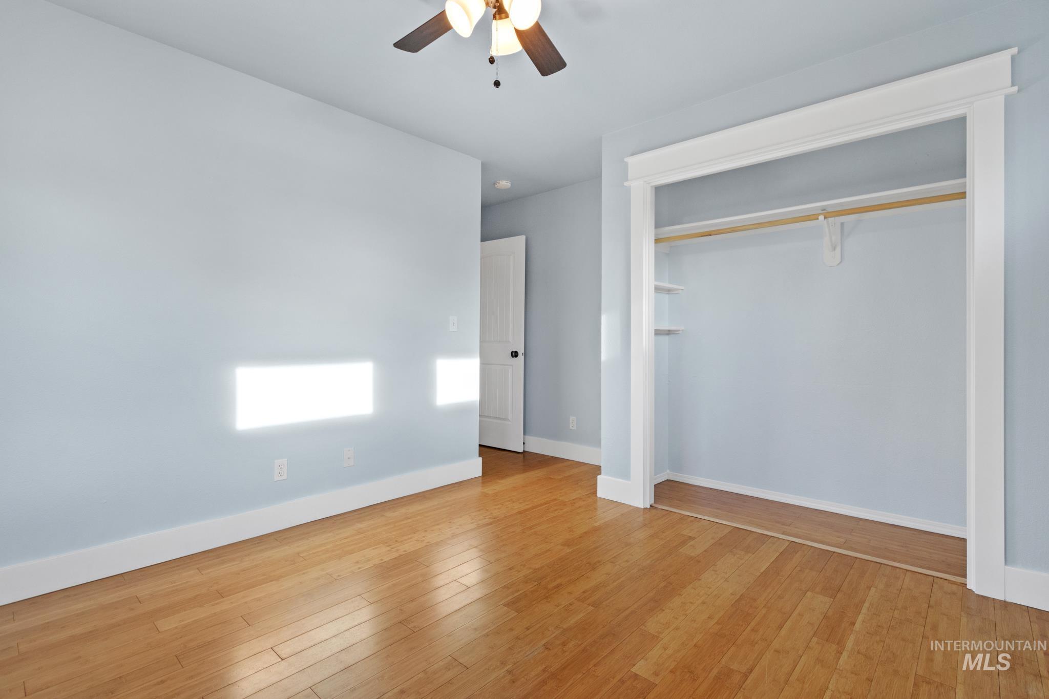 Unfurnished bedroom featuring light wood-type flooring, a closet, and ceiling fan