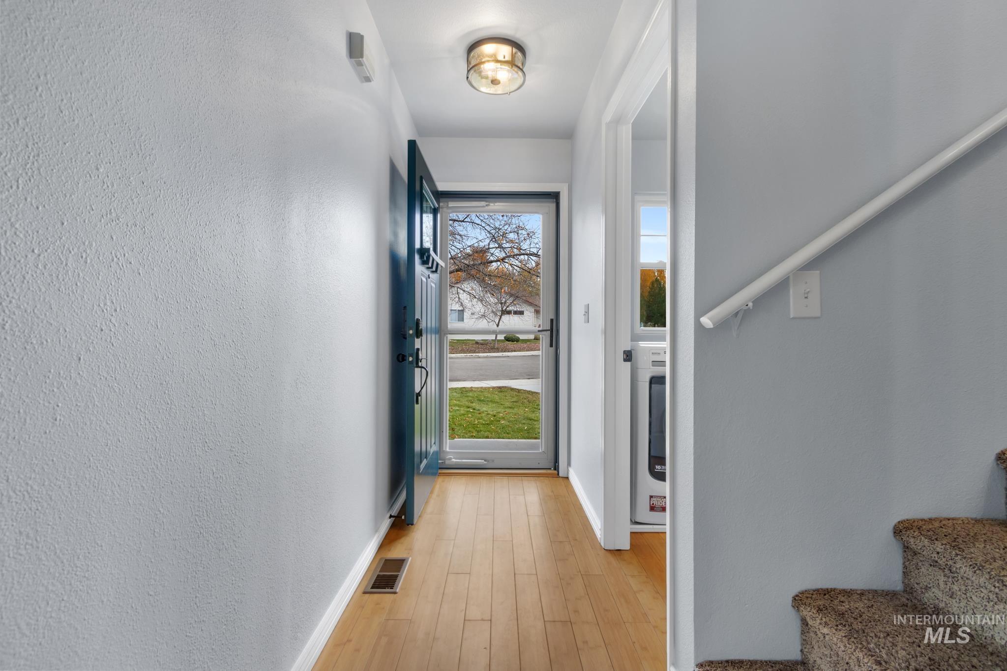 Doorway featuring stairway, wood-type flooring, and a textured wall