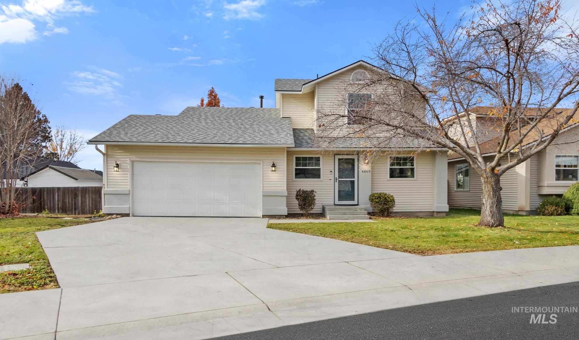 Traditional-style house with a shingled roof, driveway, and an attached garage