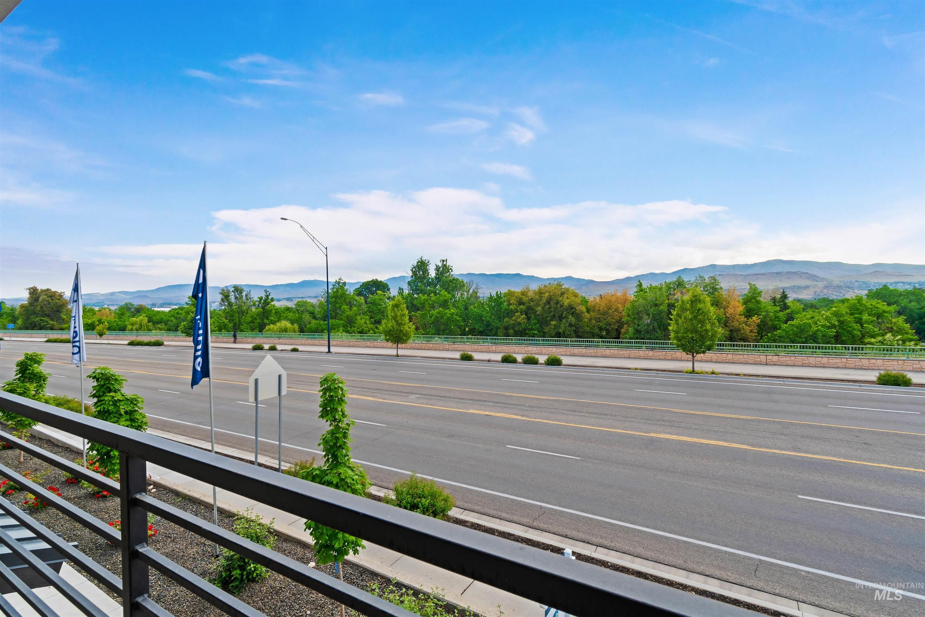 Black metal railing with horizontal balusters, featuring a street scene with a distant mountainous backdrop