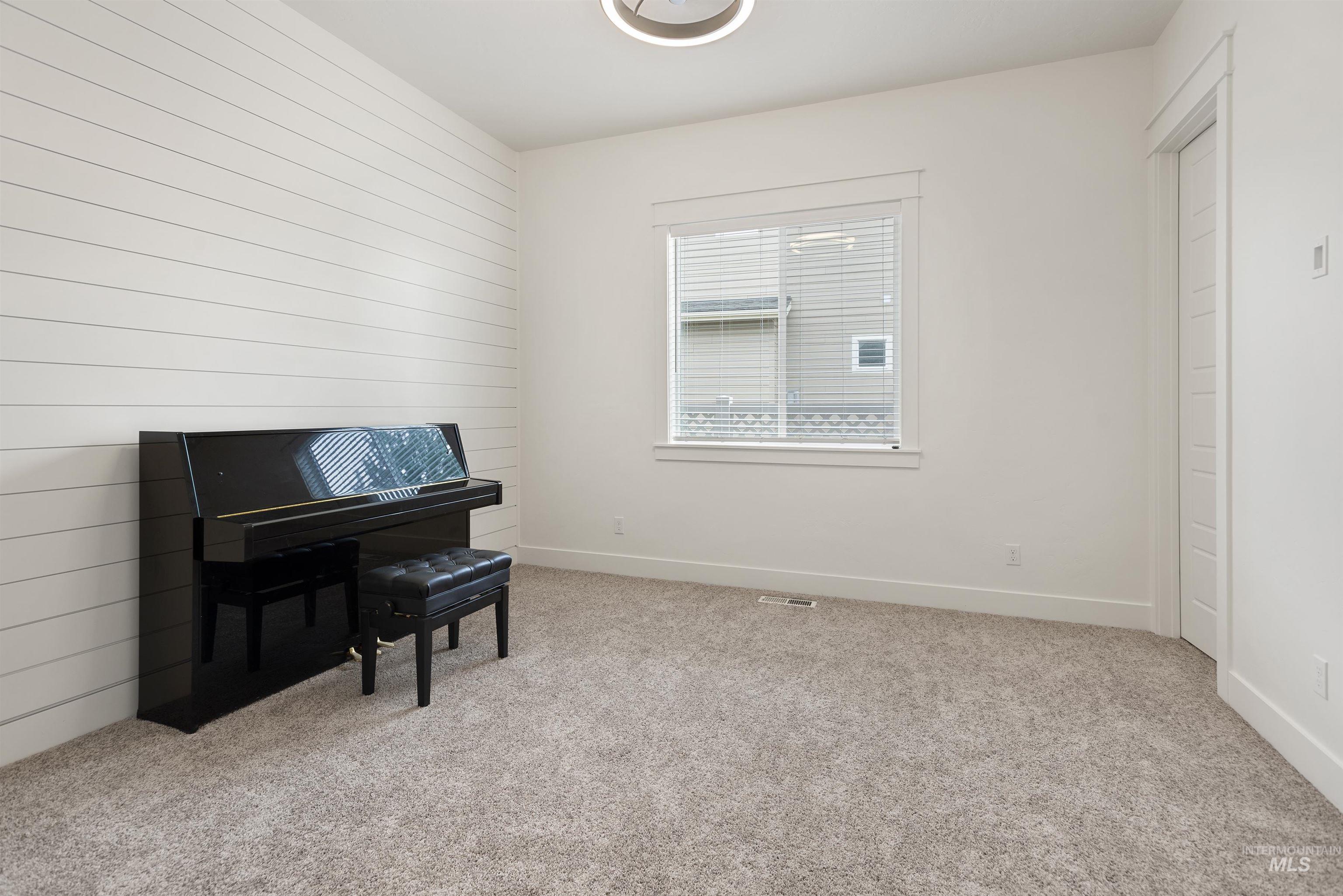 Sitting room with light colored carpet, wood walls, and an accent wall