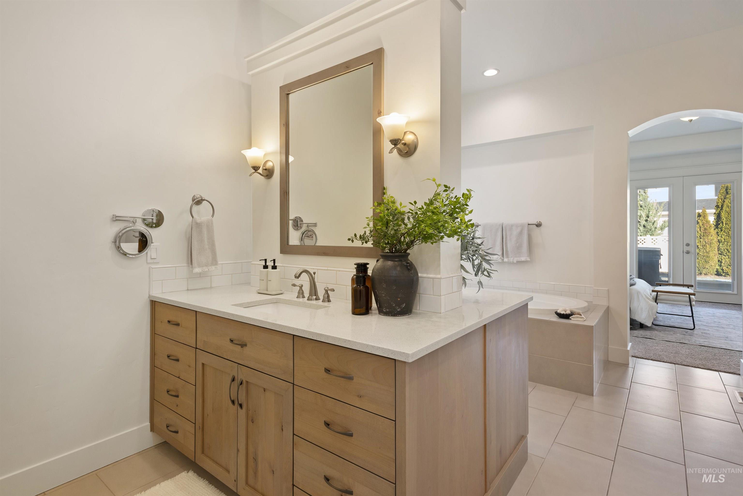 Ensuite bathroom featuring vanity, light tile patterned floors, french doors, a bath, and recessed lighting