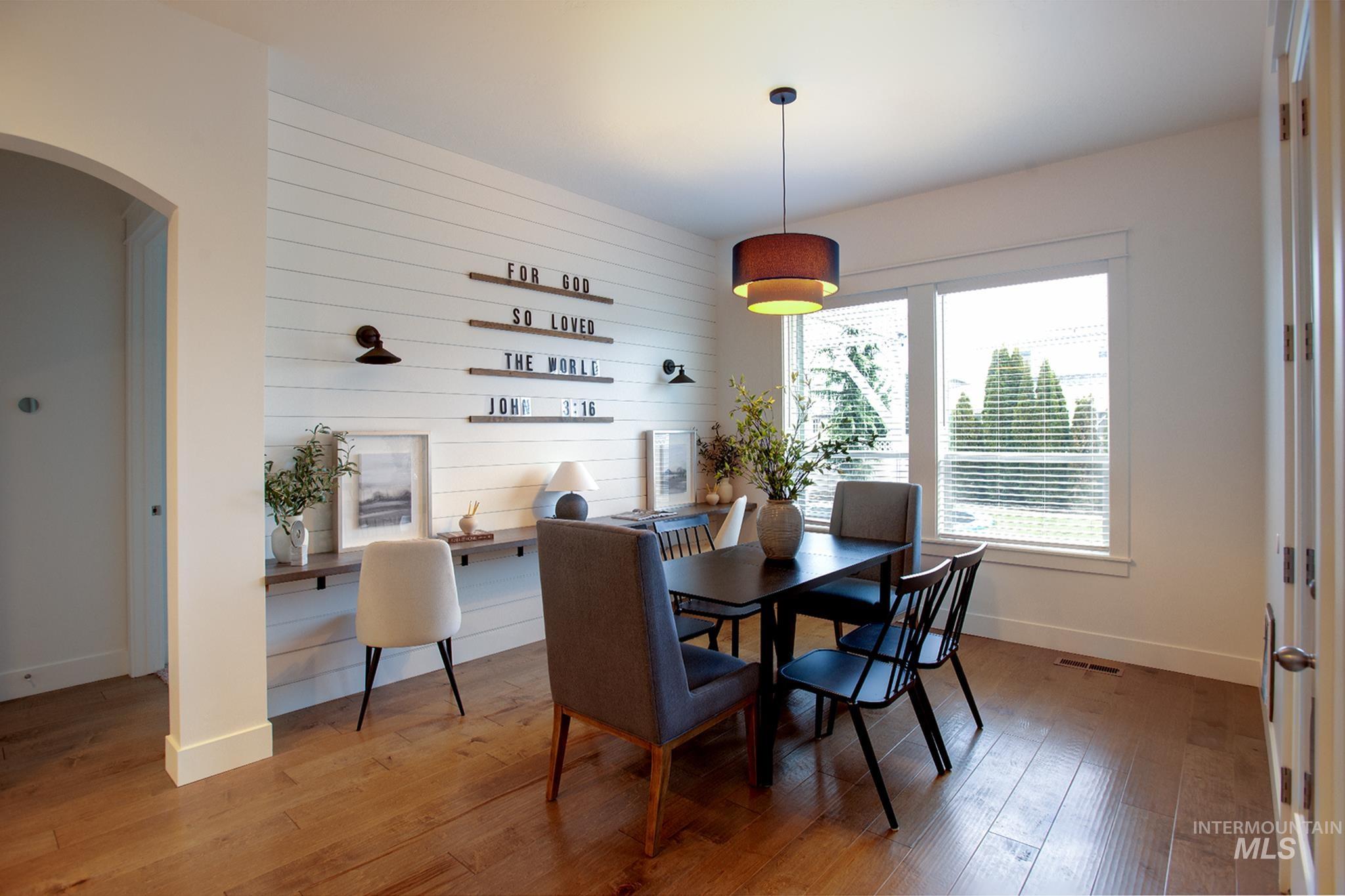Dining room featuring arched walkways, hardwood / wood-style flooring, wooden walls, and an accent wall