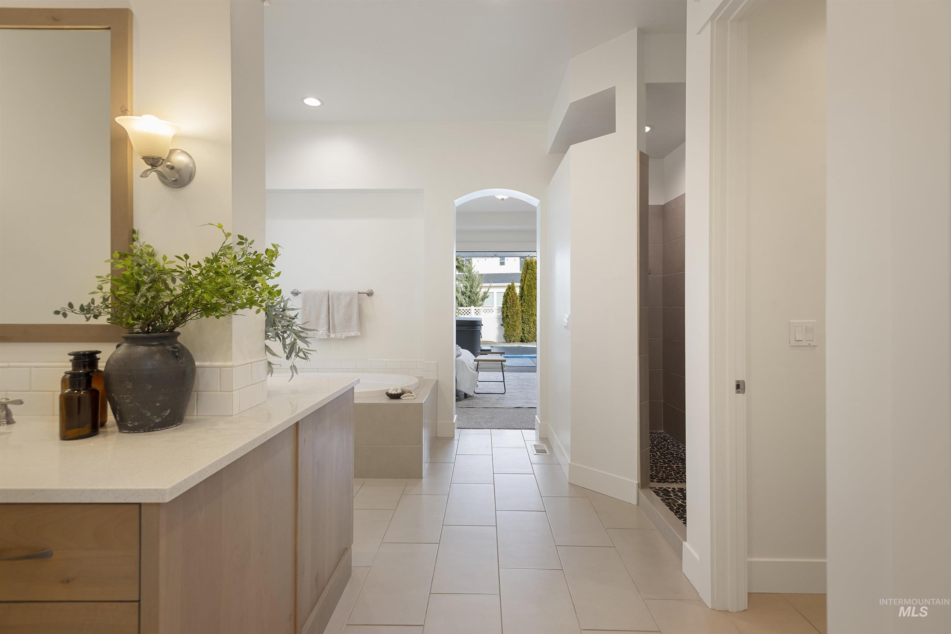 Bathroom with a bath, ensuite bath, light tile patterned flooring, tiled shower, and vanity