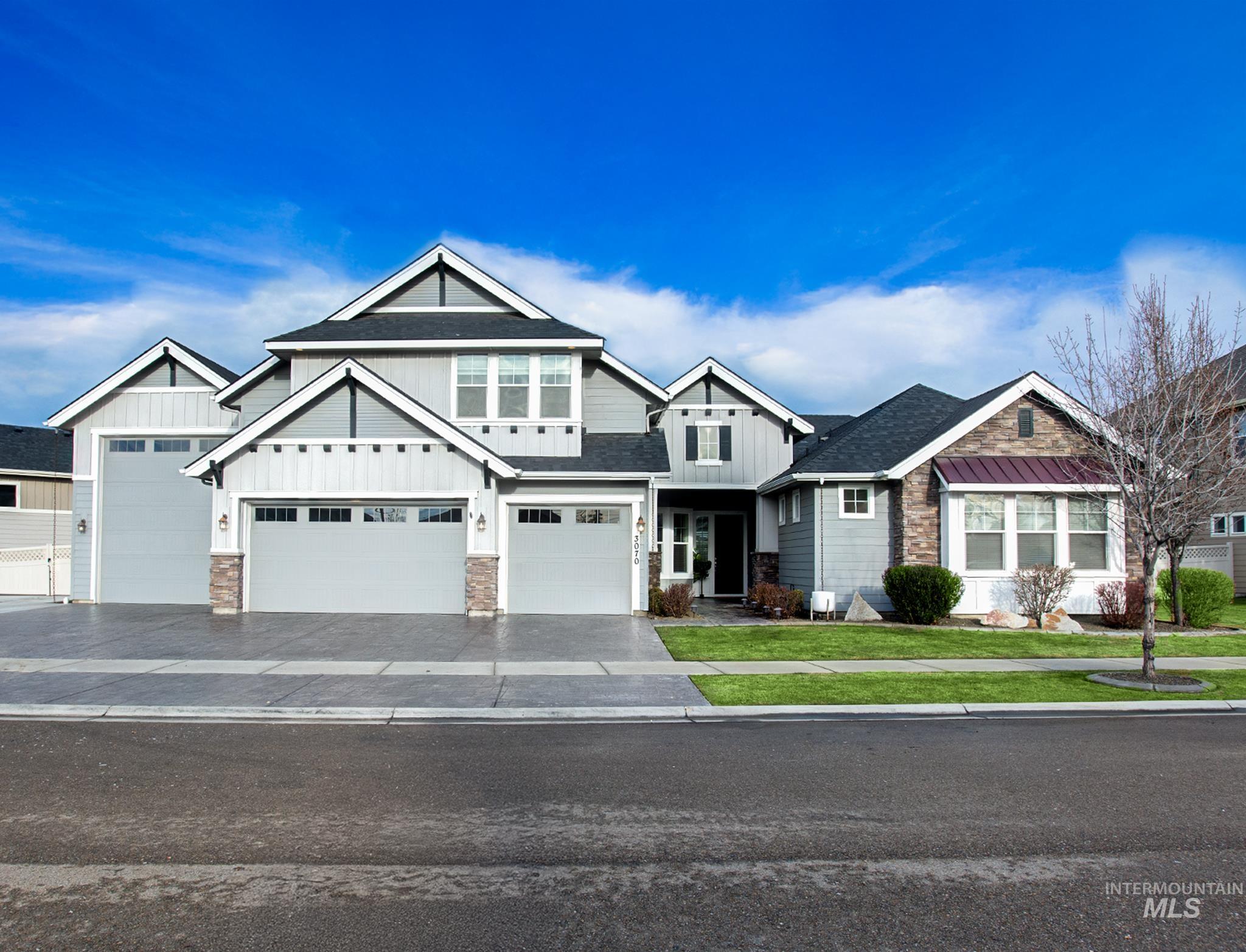 Craftsman-style house featuring board and batten siding, a front yard, asphalt driveway, roof with shingles, and stone siding