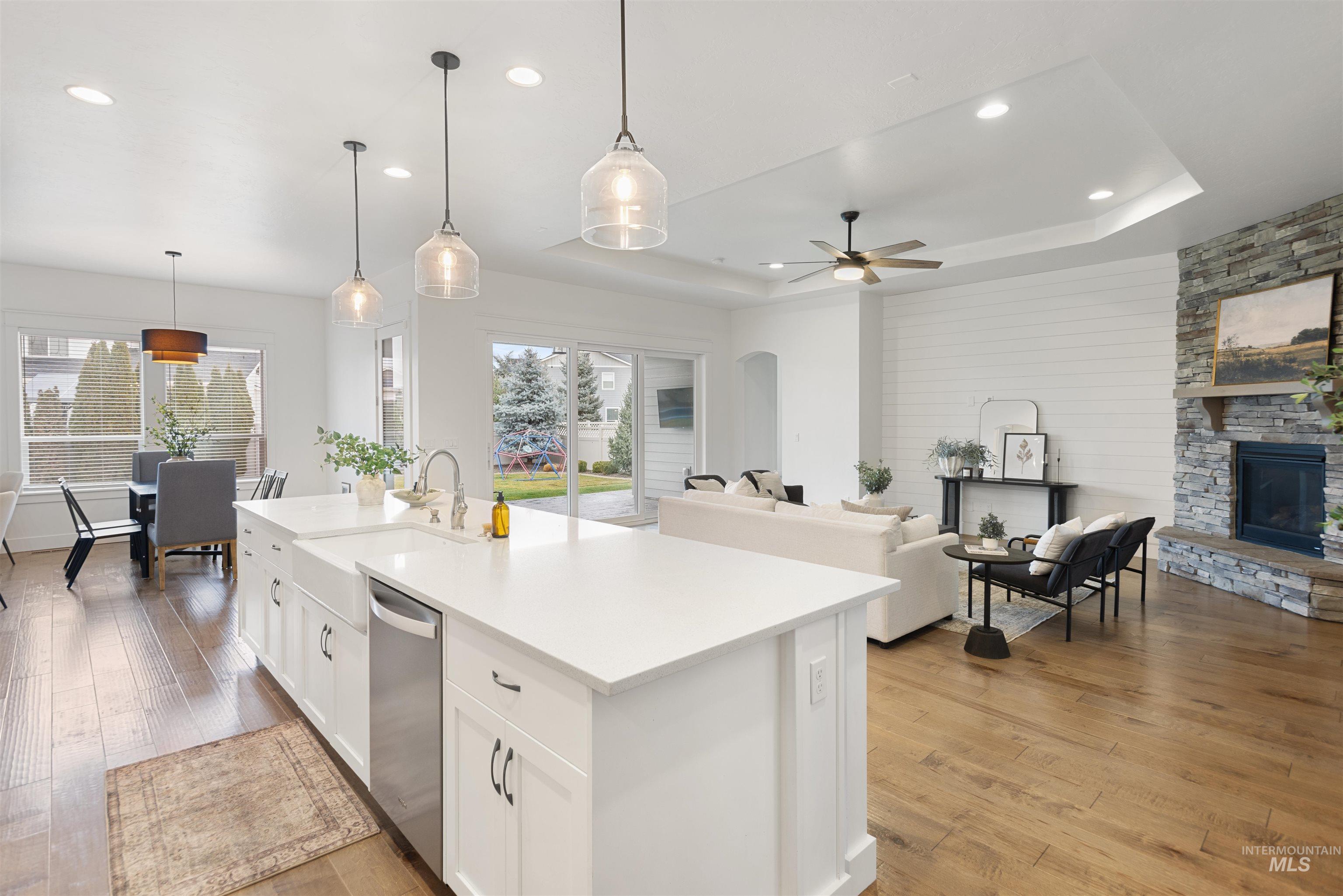 Kitchen with open floor plan, hanging light fixtures, white cabinets, light wood-style floors, and recessed lighting