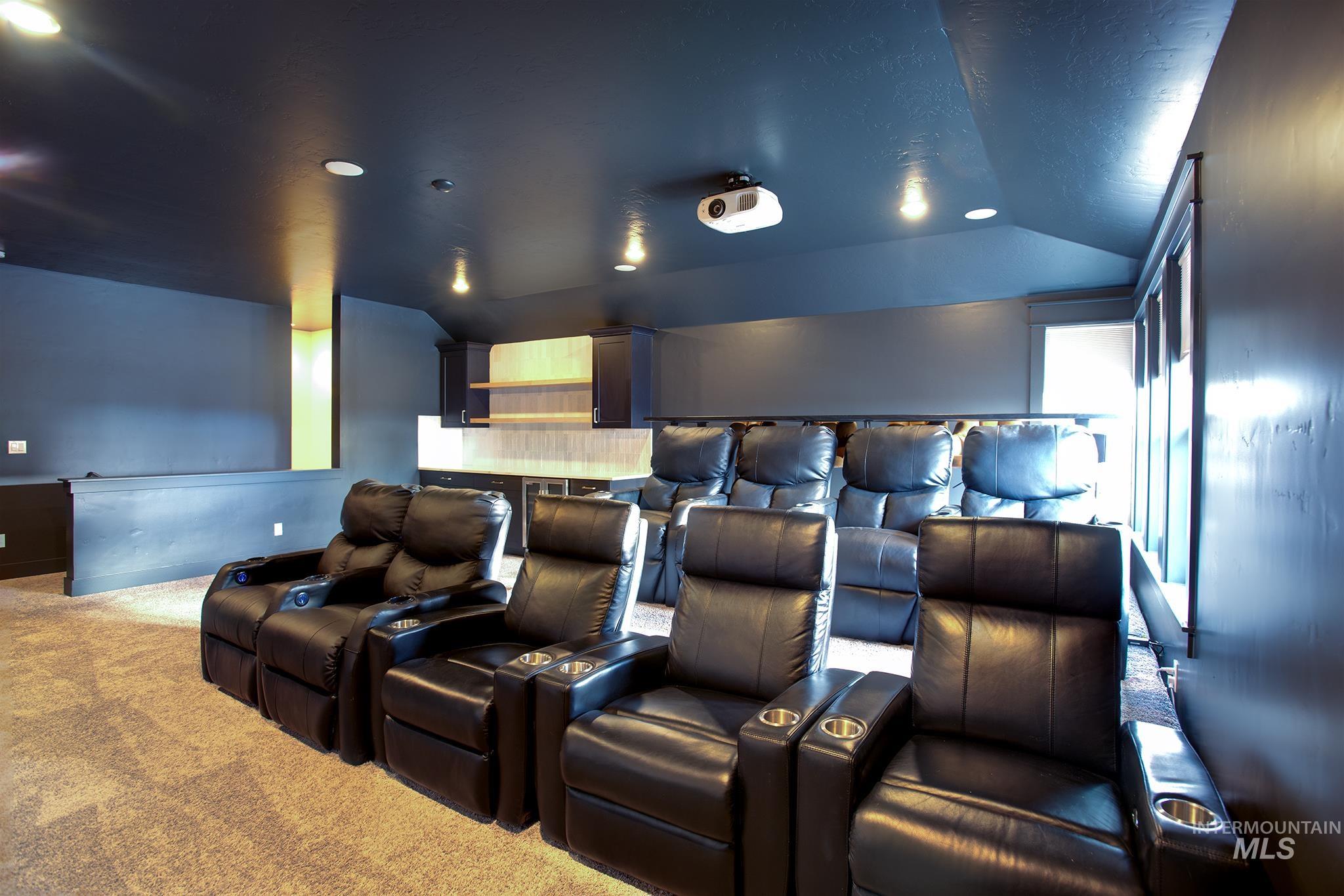 Carpeted cinema with vaulted ceiling and recessed lighting