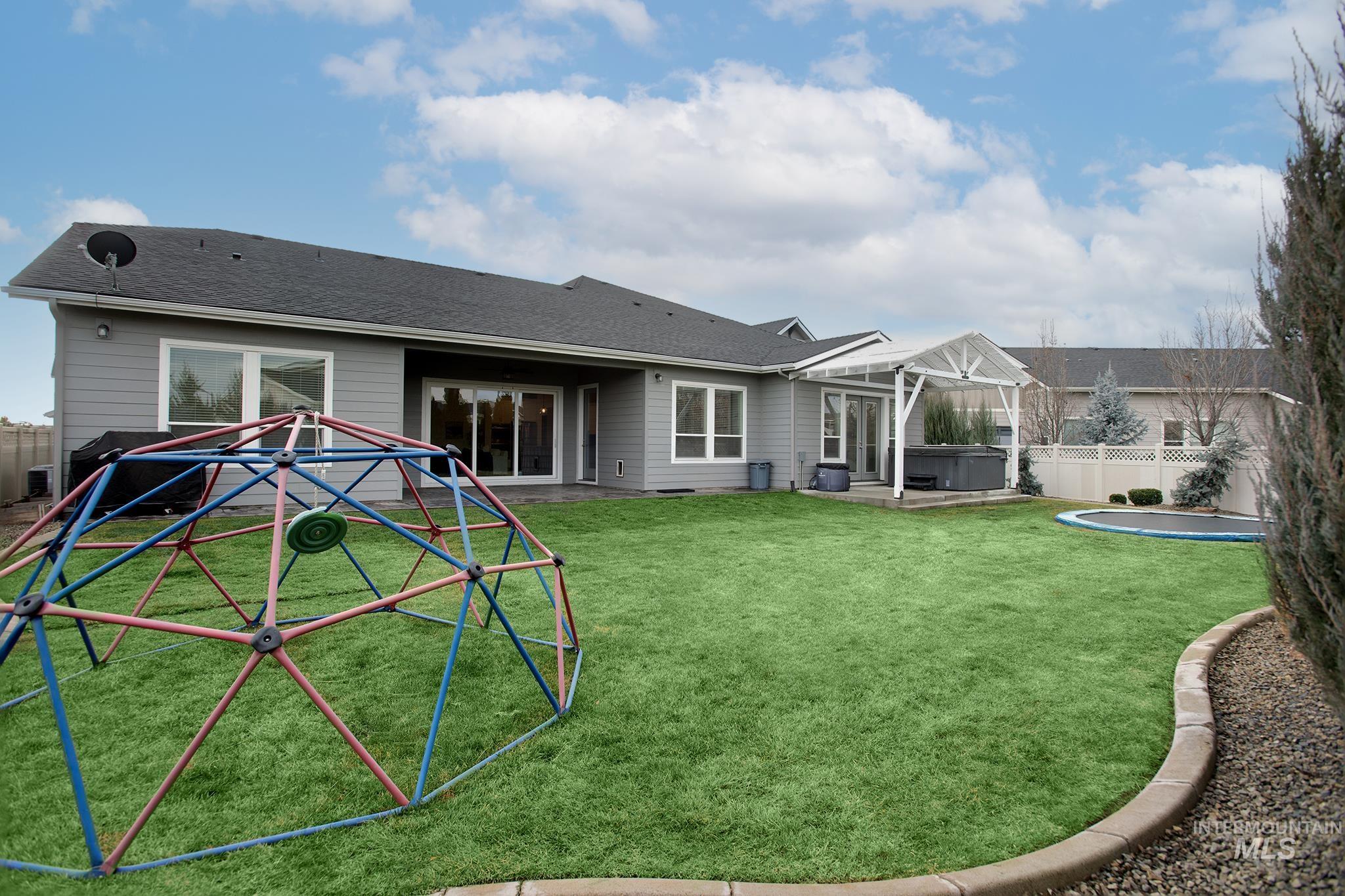 Rear view of property featuring a patio, a fenced backyard, a hot tub, and roof with shingles