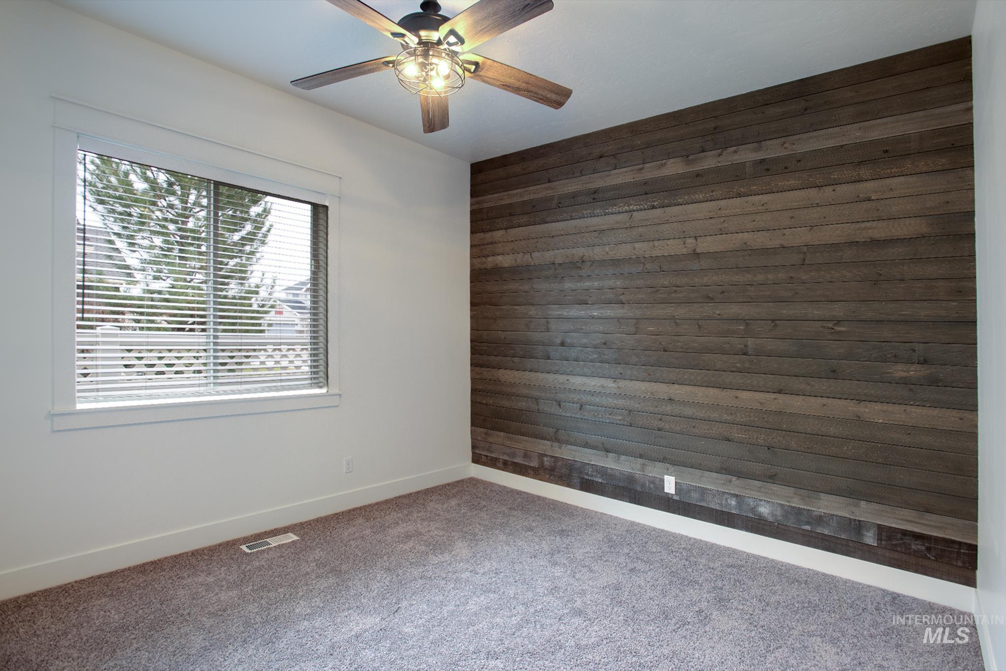 Unfurnished room with wood walls, carpet, and a ceiling fan