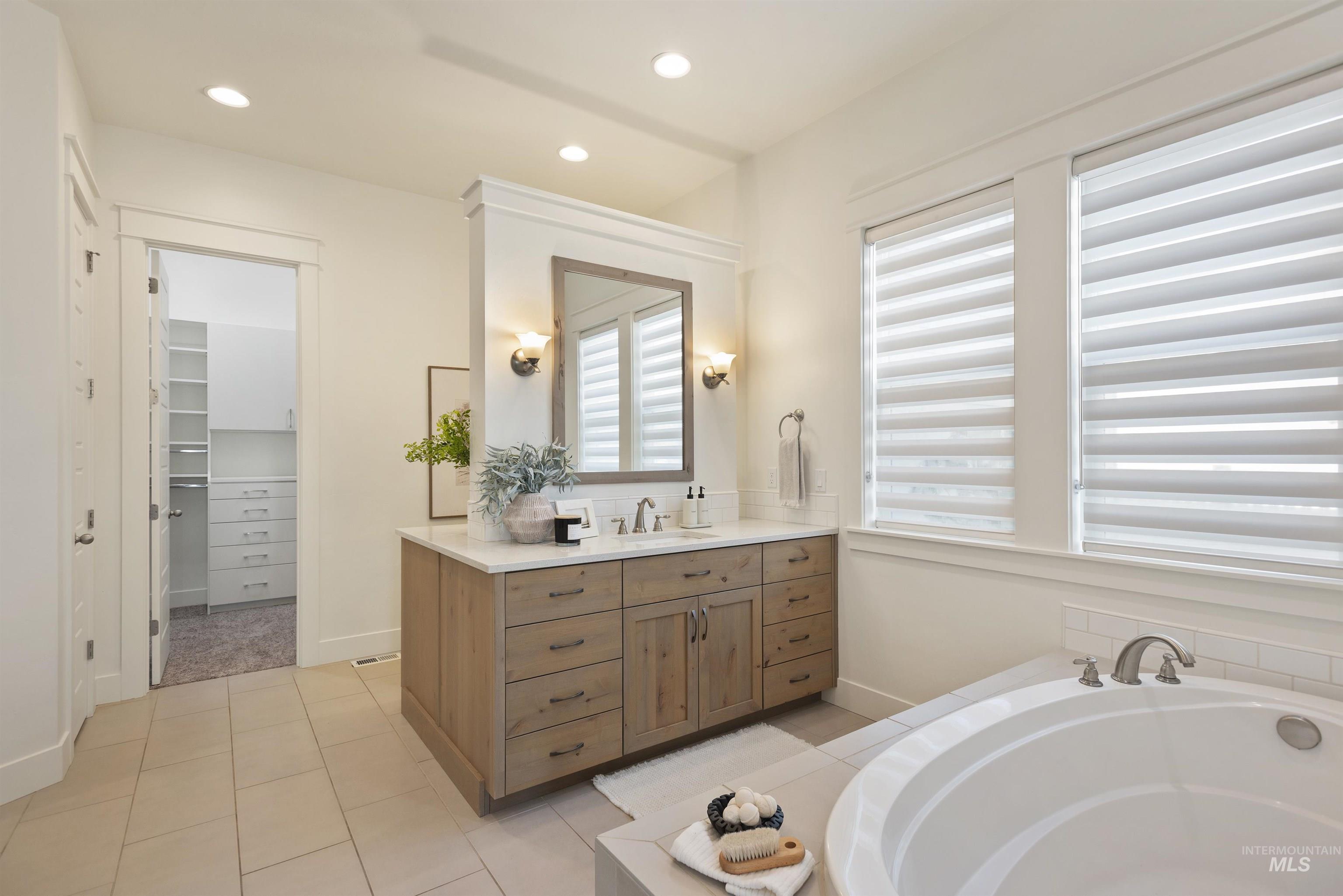 Full bath featuring vanity, a bath, recessed lighting, a spacious closet, and light tile patterned floors