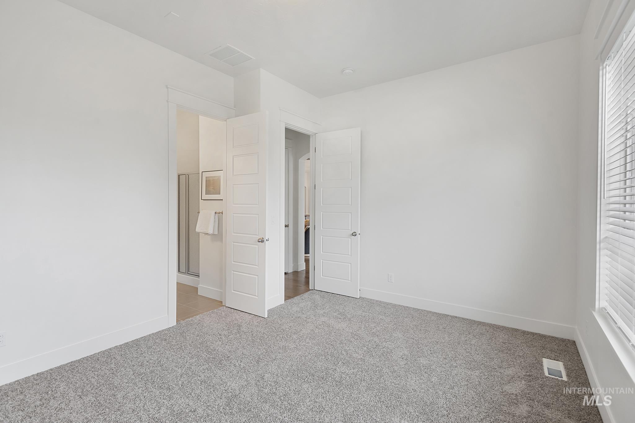 Unfurnished bedroom featuring light carpet and connected bathroom