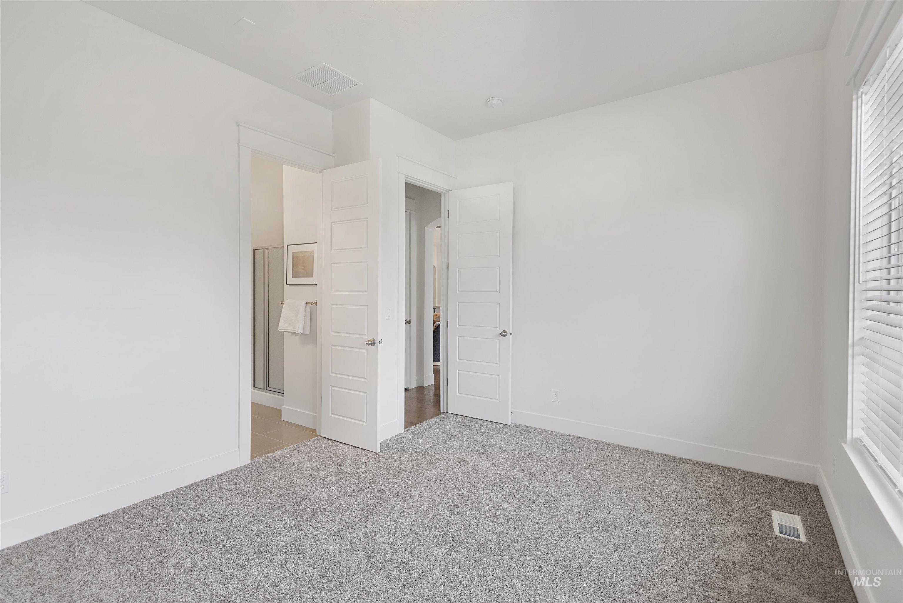 Unfurnished bedroom featuring light carpet and ensuite bathroom