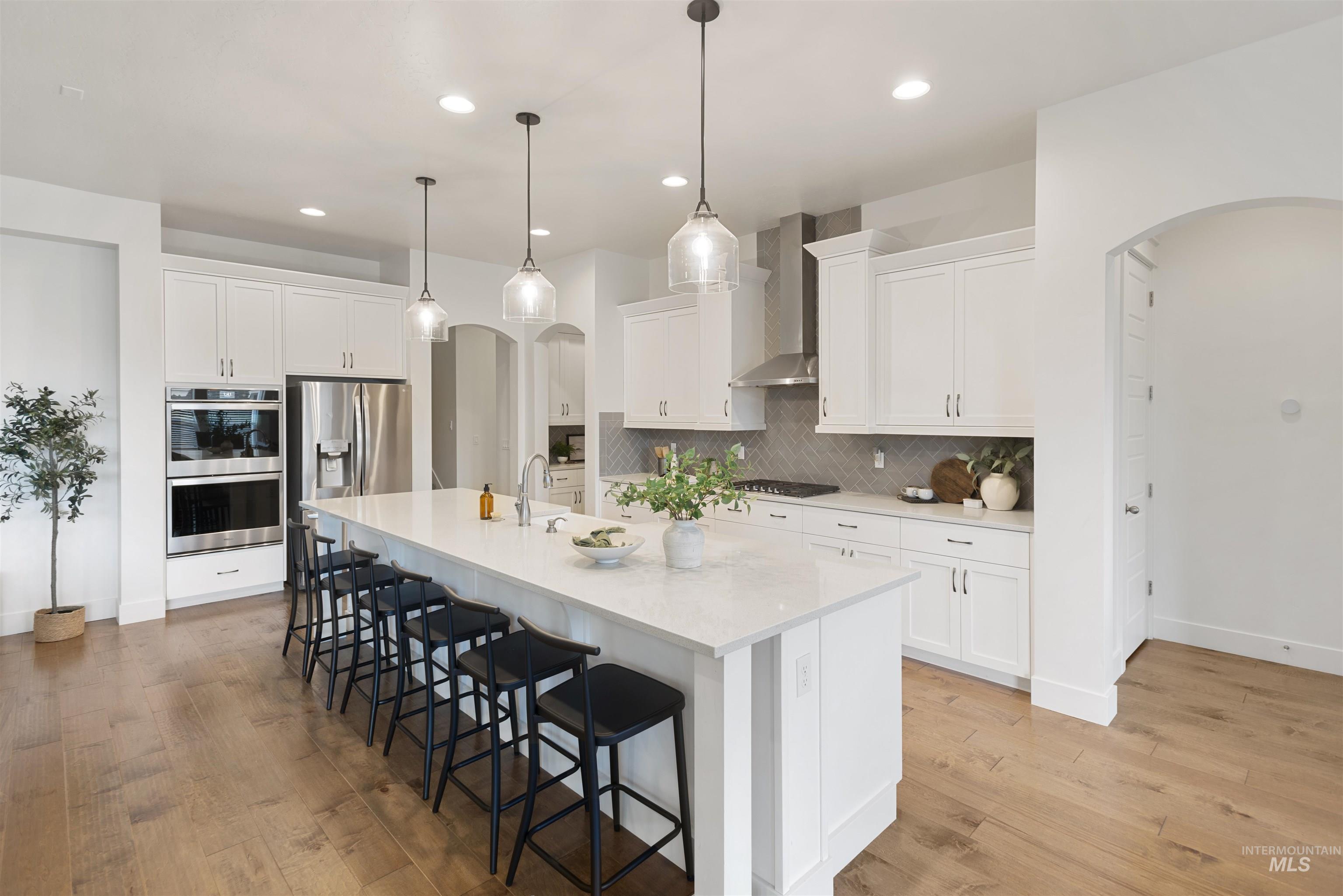 Kitchen featuring arched walkways, a kitchen bar, white cabinets, appliances with stainless steel finishes, and recessed lighting