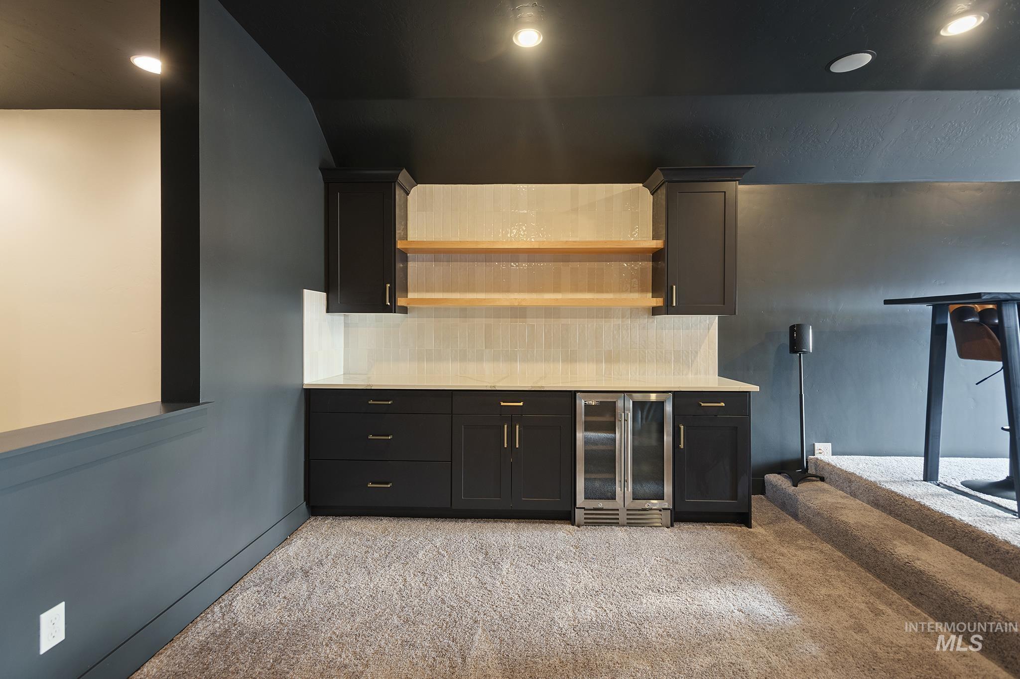 Bar area with backsplash, dark cabinets, beverage cooler, open shelves, and recessed lighting