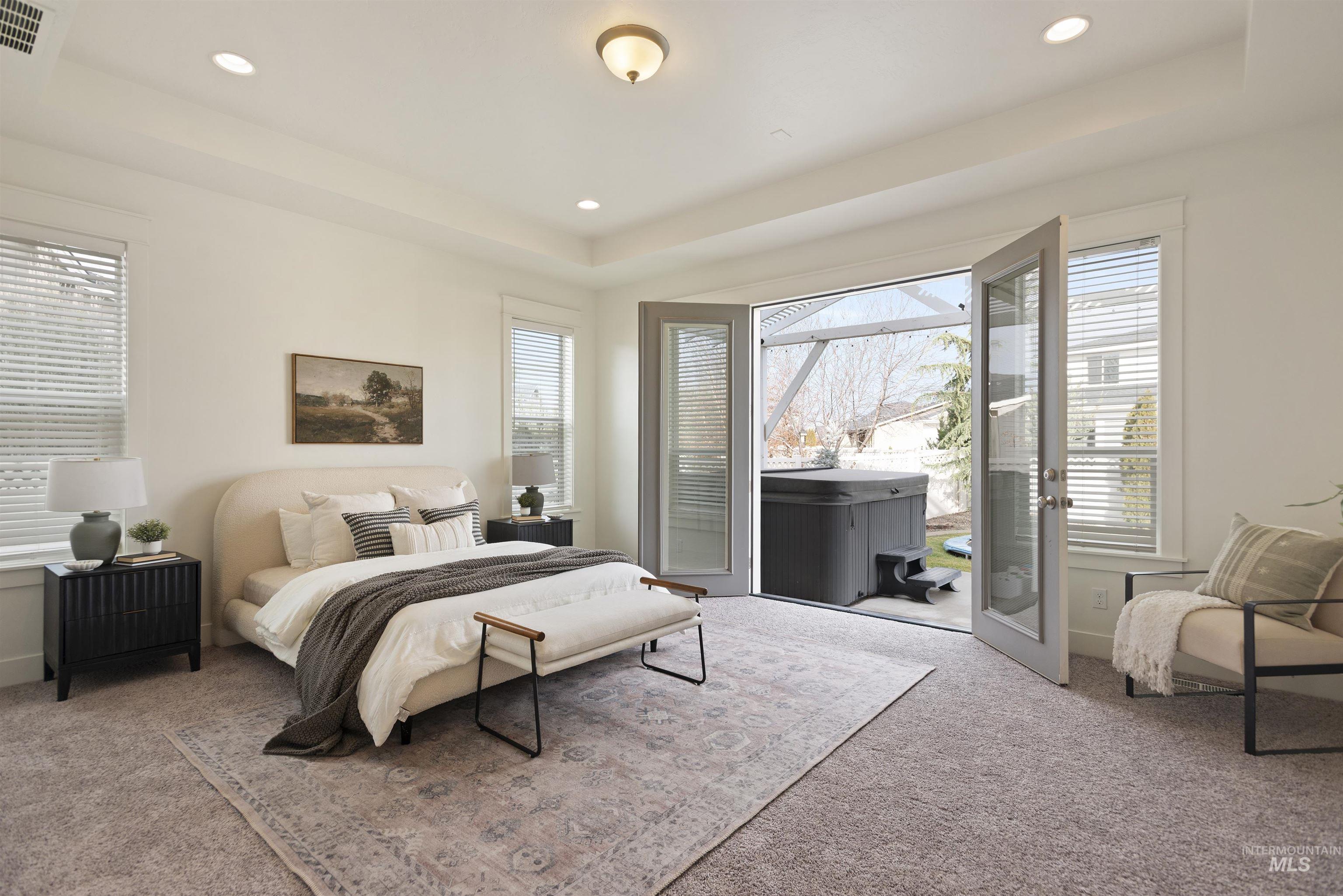 Bedroom with a tray ceiling, access to exterior, carpet, multiple windows, and recessed lighting