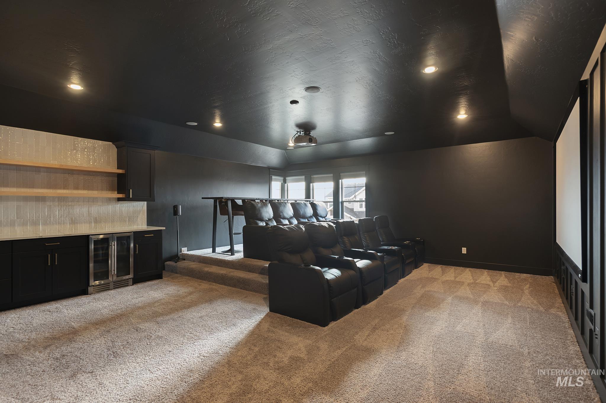 Cinema featuring light colored carpet, bar, beverage cooler, a textured ceiling, and recessed lighting