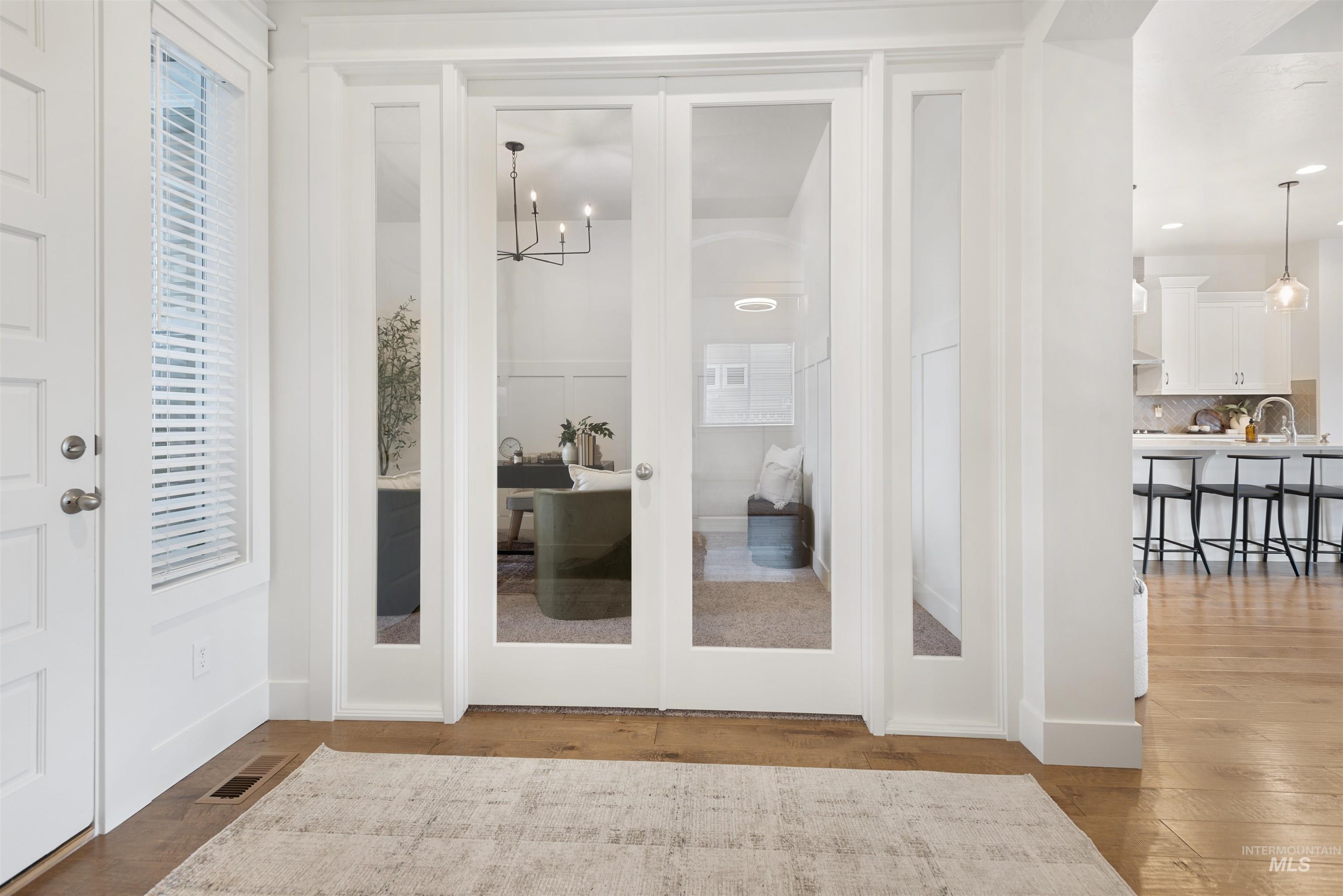 Entryway featuring light wood-style floors, a chandelier, and french doors