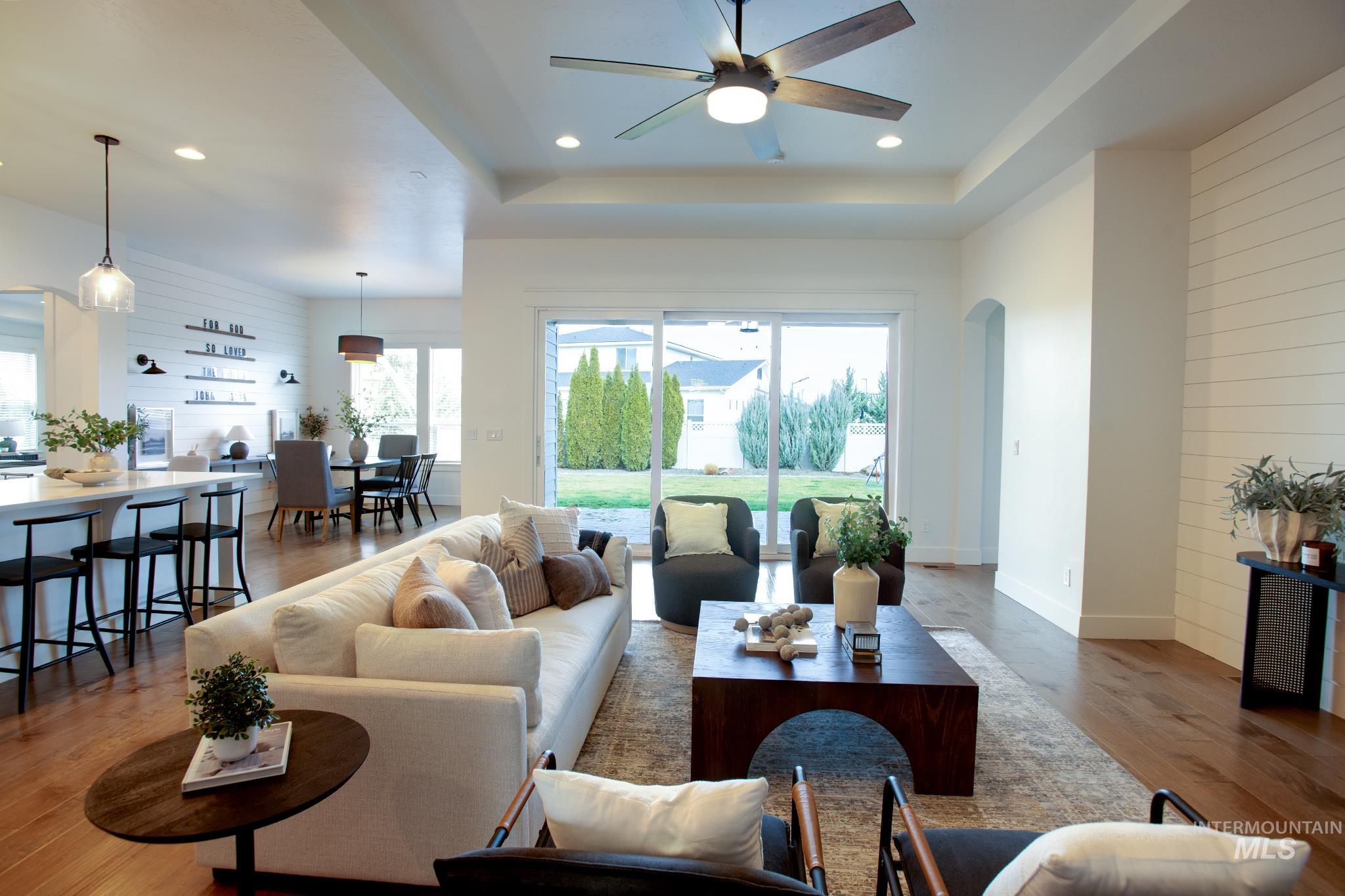 Living room with wood finished floors, a raised ceiling, healthy amount of natural light, wooden walls, and recessed lighting