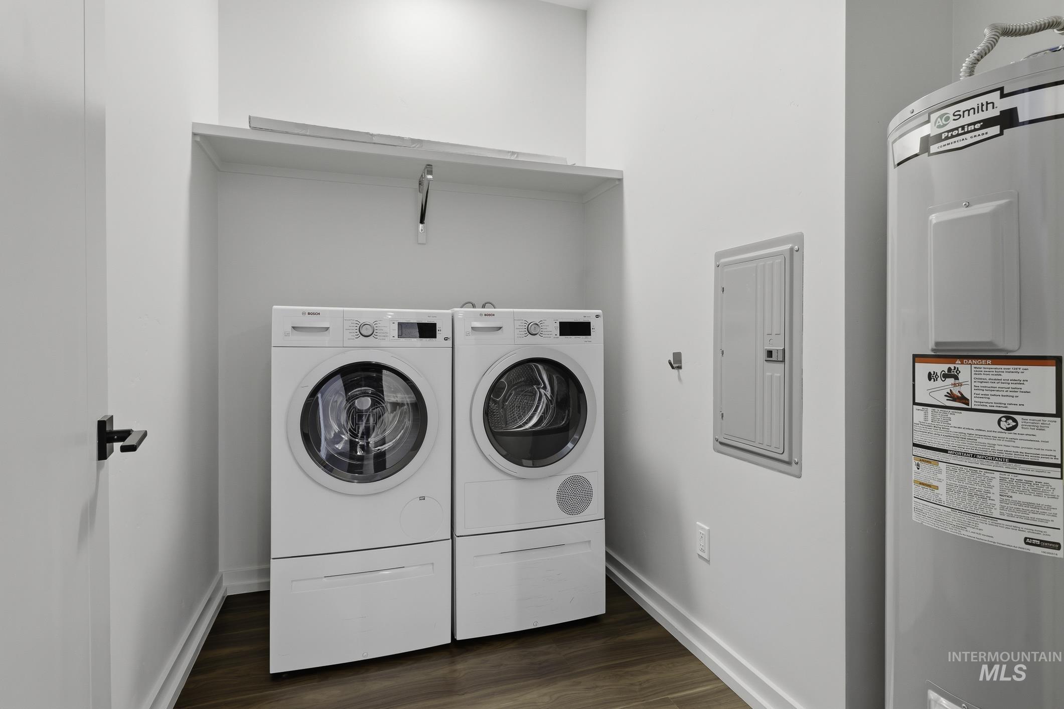 Laundry area featuring water heater, electric panel, dark wood-type flooring, and washer and clothes dryer