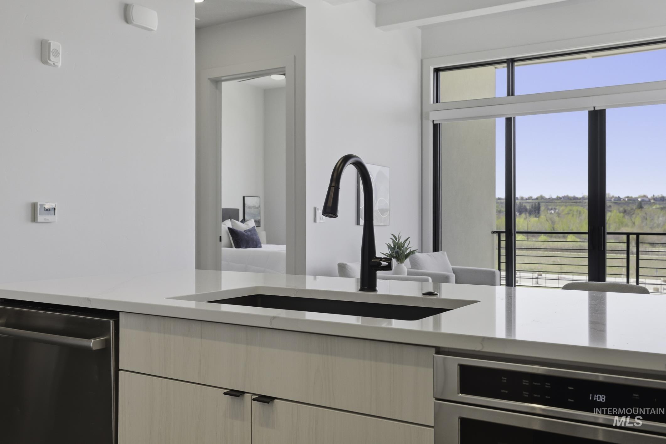 Kitchen featuring light stone countertops, stainless steel appliances, modern cabinets, and beam ceiling