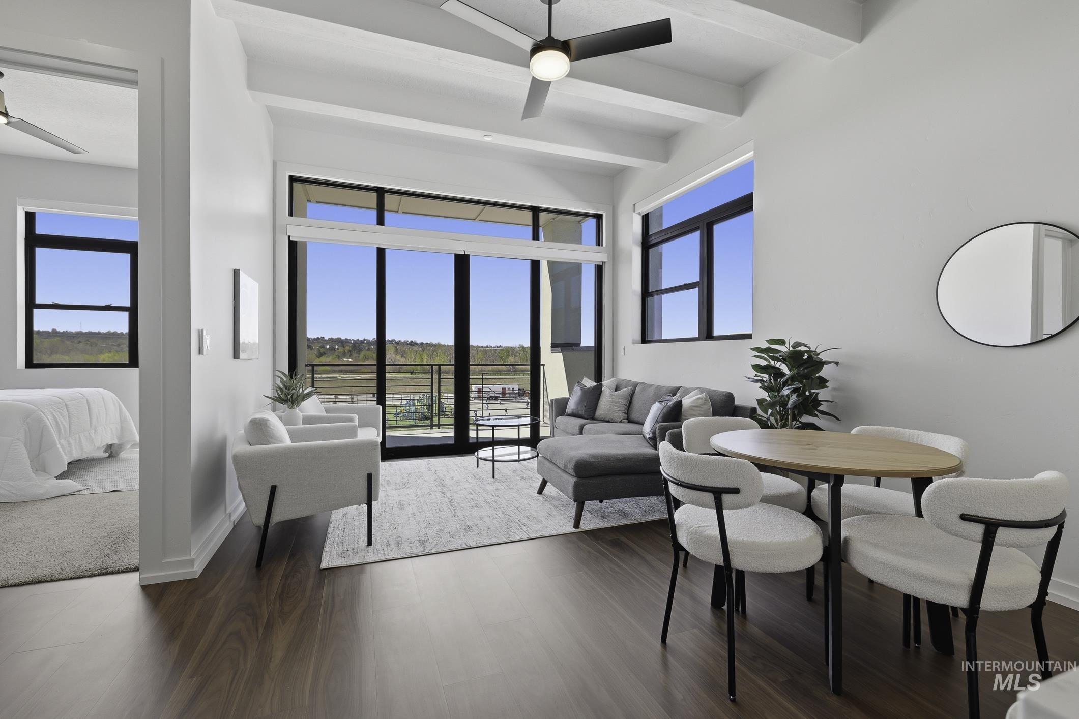 Living area with a ceiling fan, beamed ceiling, and dark wood finished floors