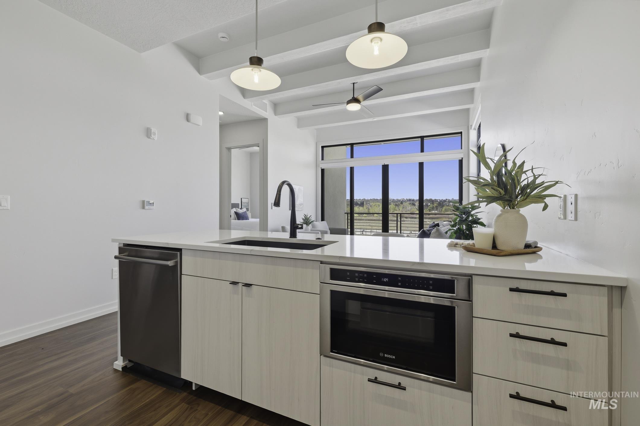 Kitchen with decorative light fixtures, stainless steel appliances, a peninsula, light stone countertops, and a ceiling fan