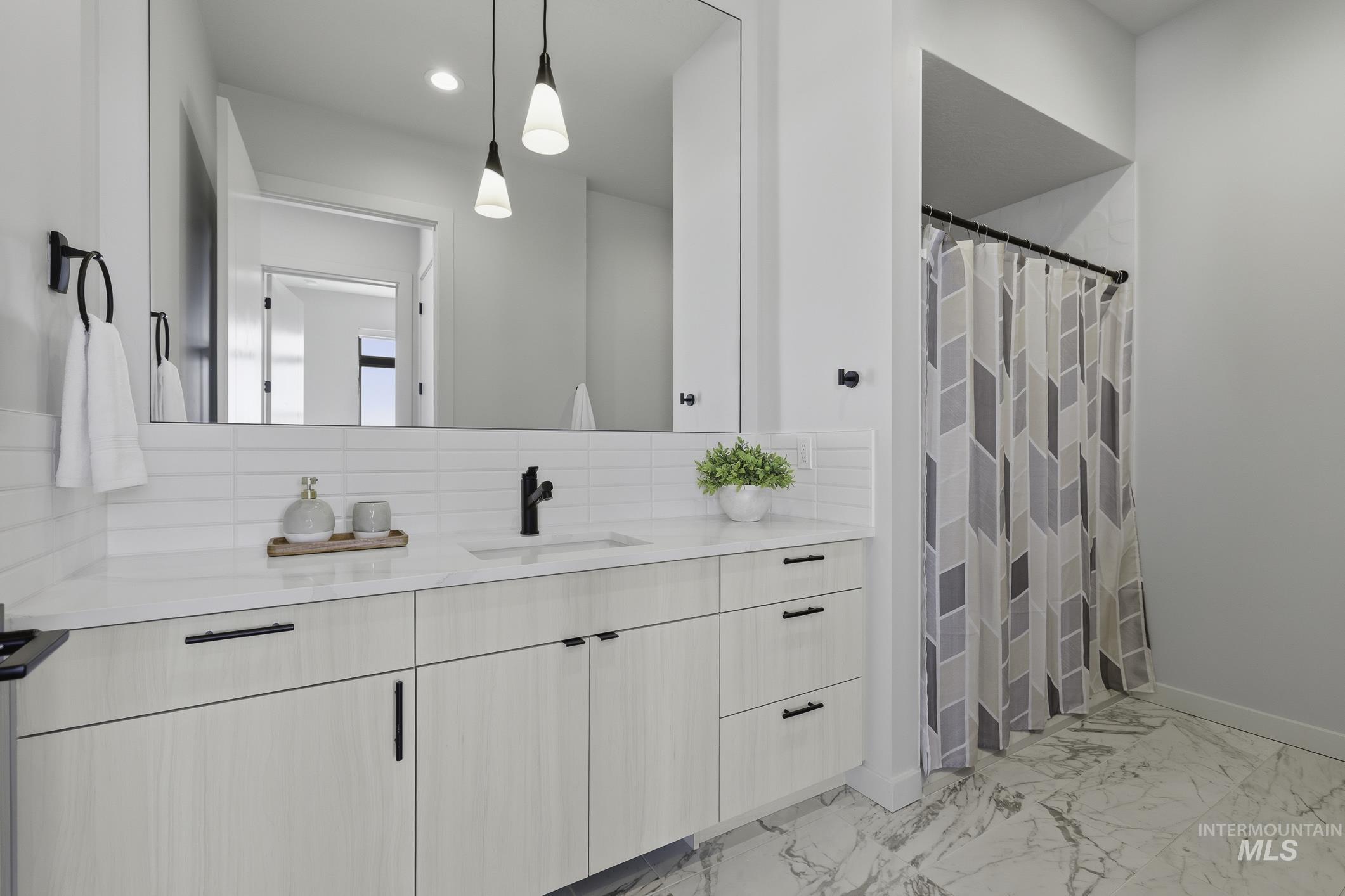 Bathroom with a shower with curtain, vanity, light marble finish flooring, decorative backsplash, and recessed lighting