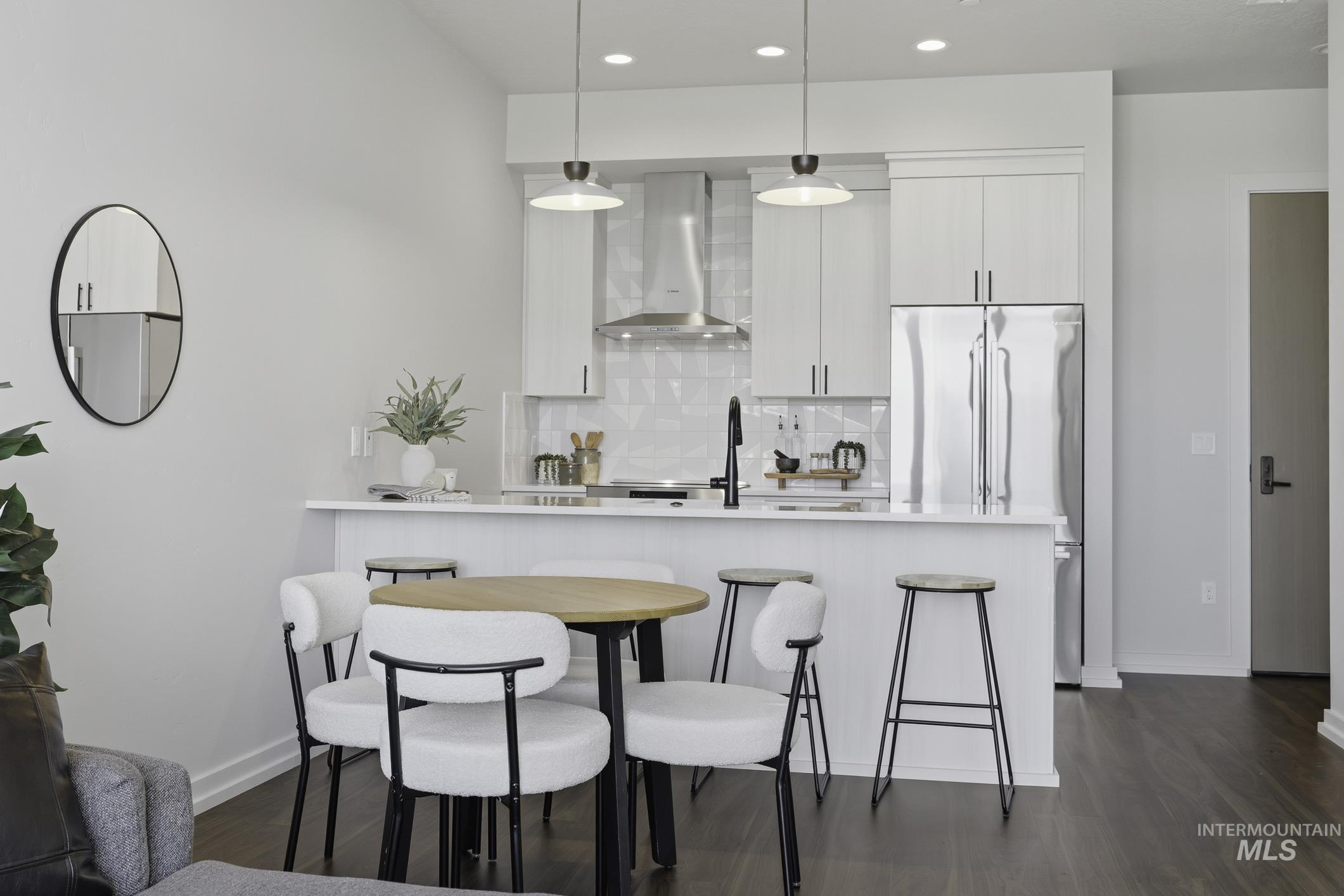 Kitchen featuring a breakfast bar, dark wood finished floors, pendant lighting, backsplash, and built in fridge