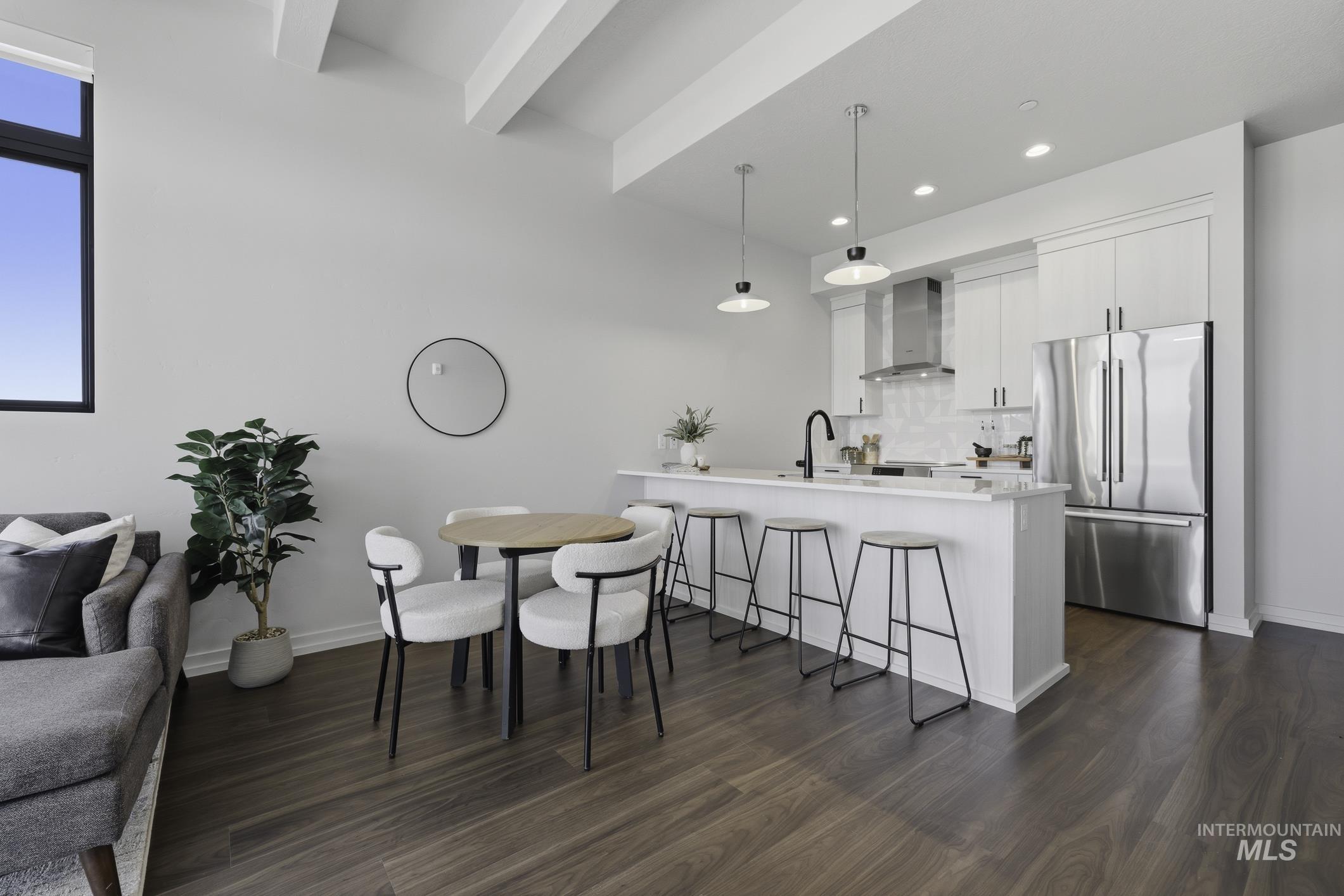 Kitchen featuring white cabinetry, freestanding refrigerator, a kitchen breakfast bar, open floor plan, and light stone countertops