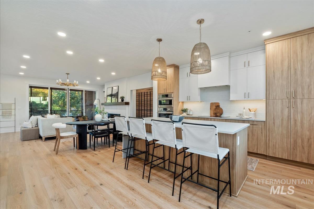 Kitchen featuring white cabinets, a chandelier, light brown cabinetry, hanging light fixtures, and a breakfast bar area