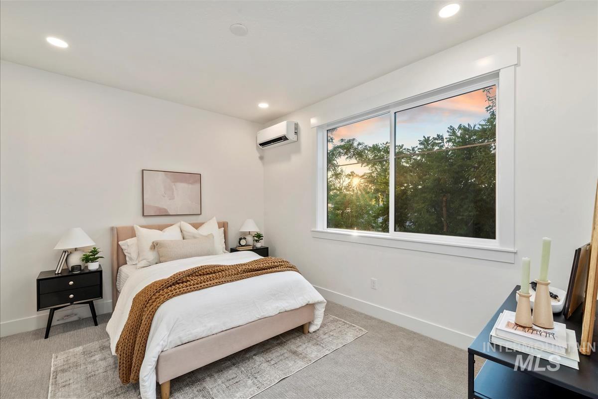 Bedroom with light carpet, recessed lighting, and a wall mounted AC