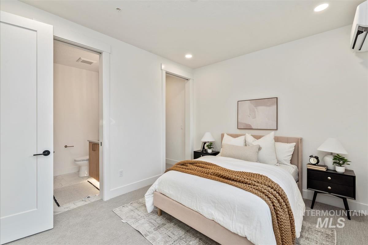 Bedroom with carpet flooring, a wall mounted AC, and recessed lighting