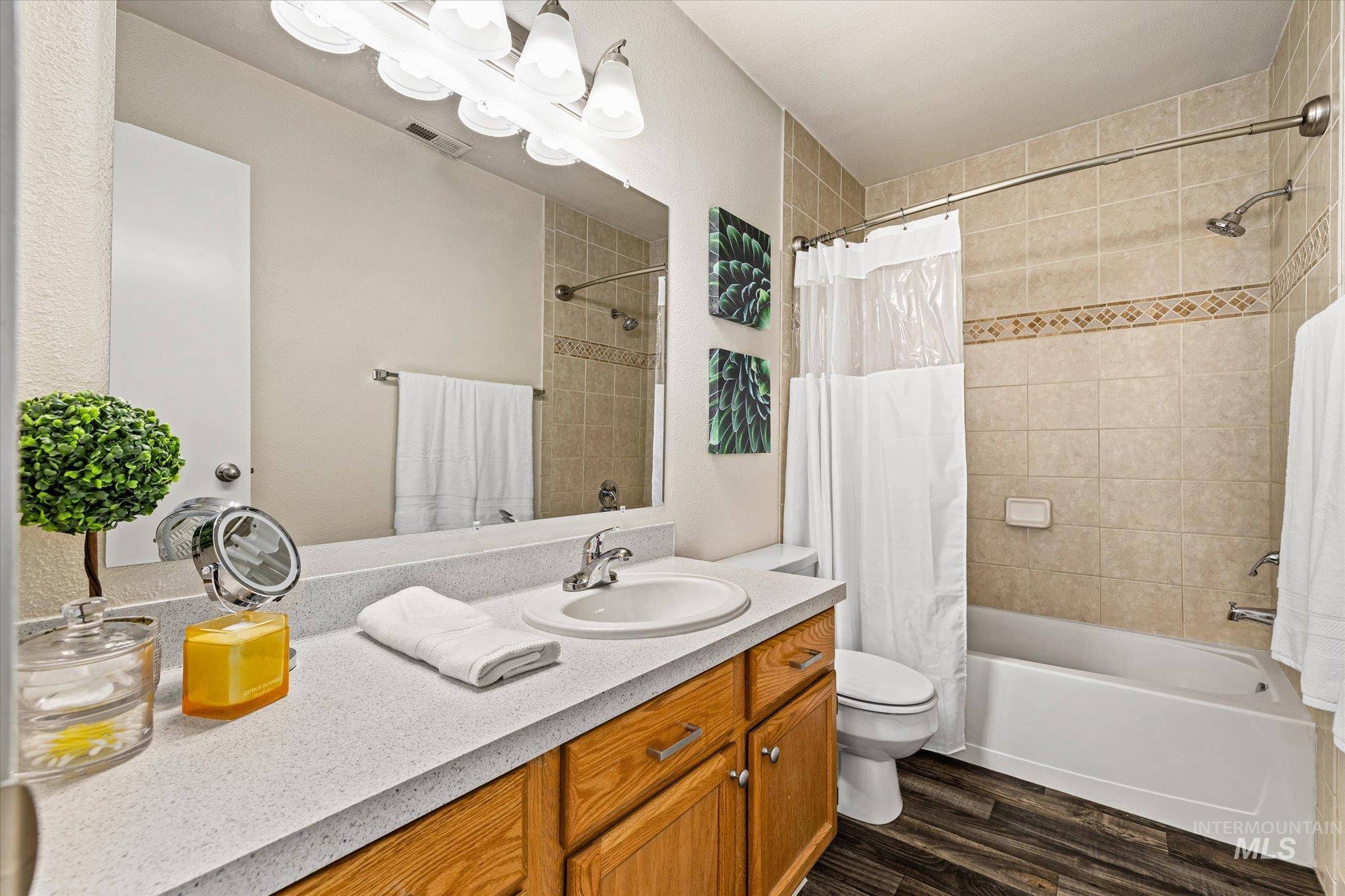 Bathroom featuring vanity, shower / bath combo with shower curtain, and dark wood-style flooring