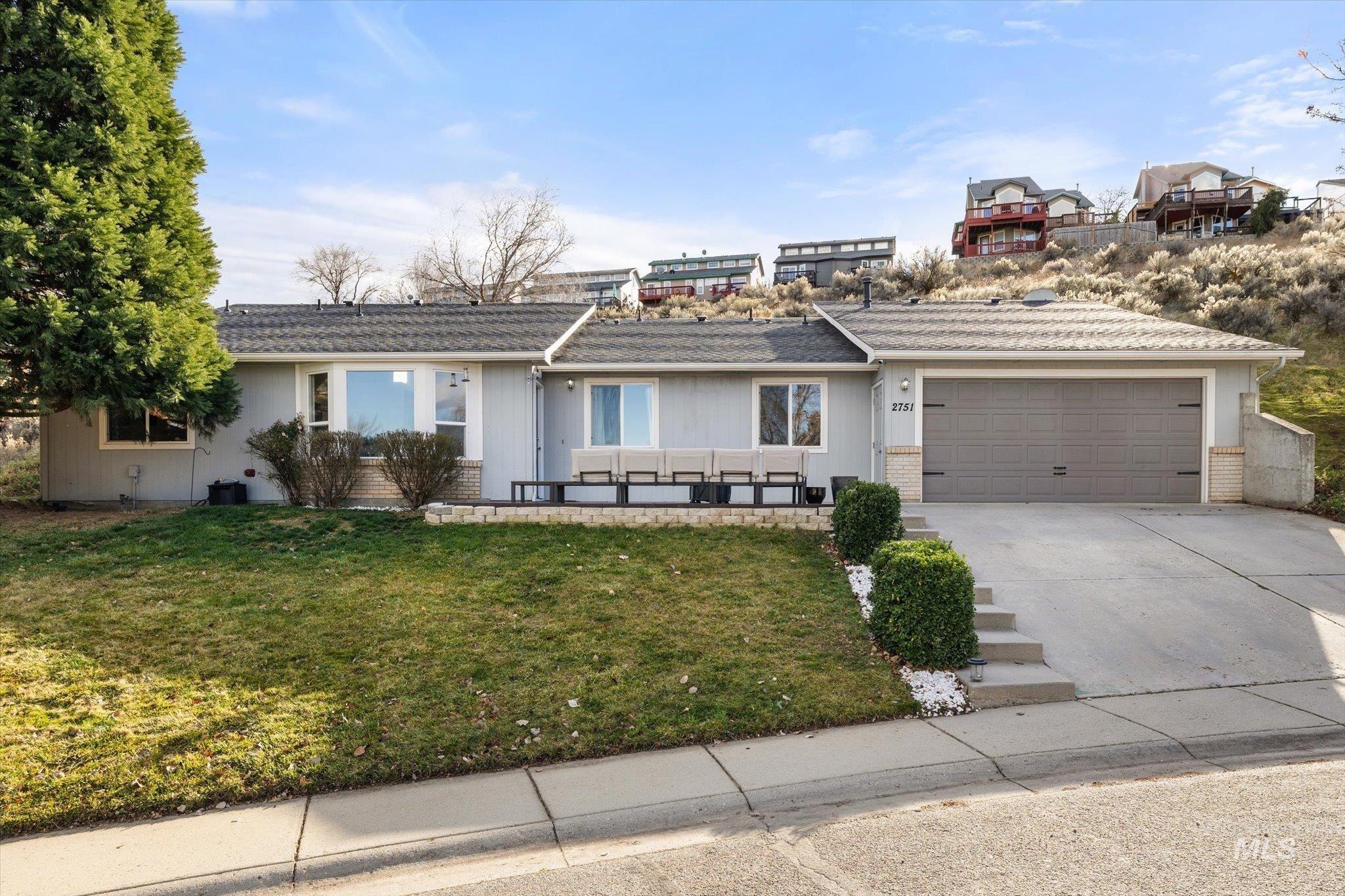 Single story home featuring driveway, a garage, a front lawn, and brick siding