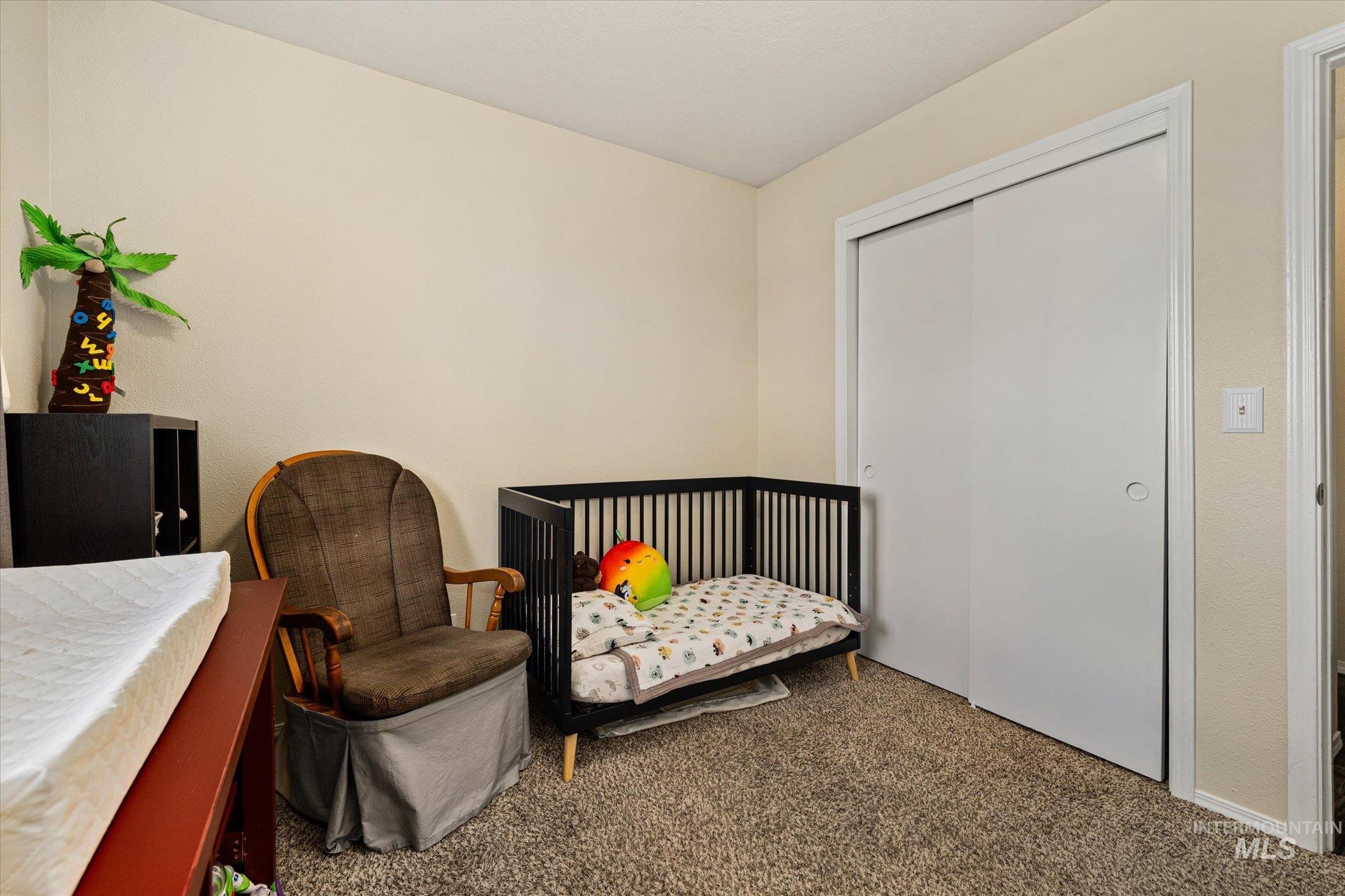 Bedroom with carpet, a closet, and a nursery area