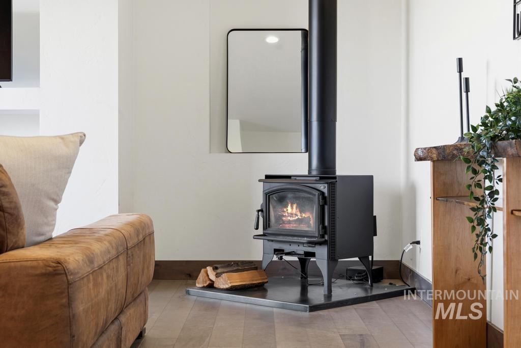 Freestanding black wood-burning stove on a dark hearth, featuring a visible flame