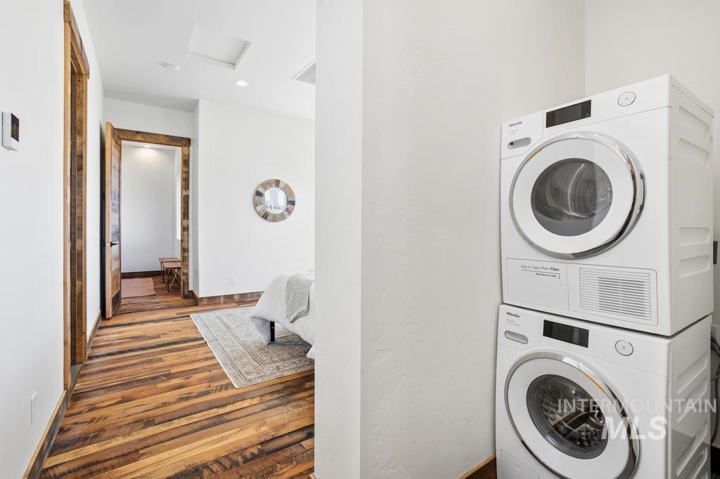 Built-in stacked washer and dryer unit, white walls, and wood-finish flooring