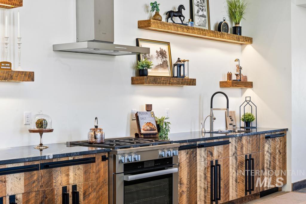 Kitchen featuring wood-finish cabinetry with black hardware, stainless steel range, and a coordinating stainless steel range hood