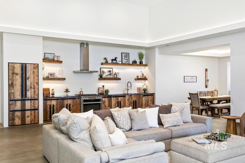 Open-concept living space featuring a partial kitchen with wood-finish cabinetry, stainless steel appliances, and integrated shelving