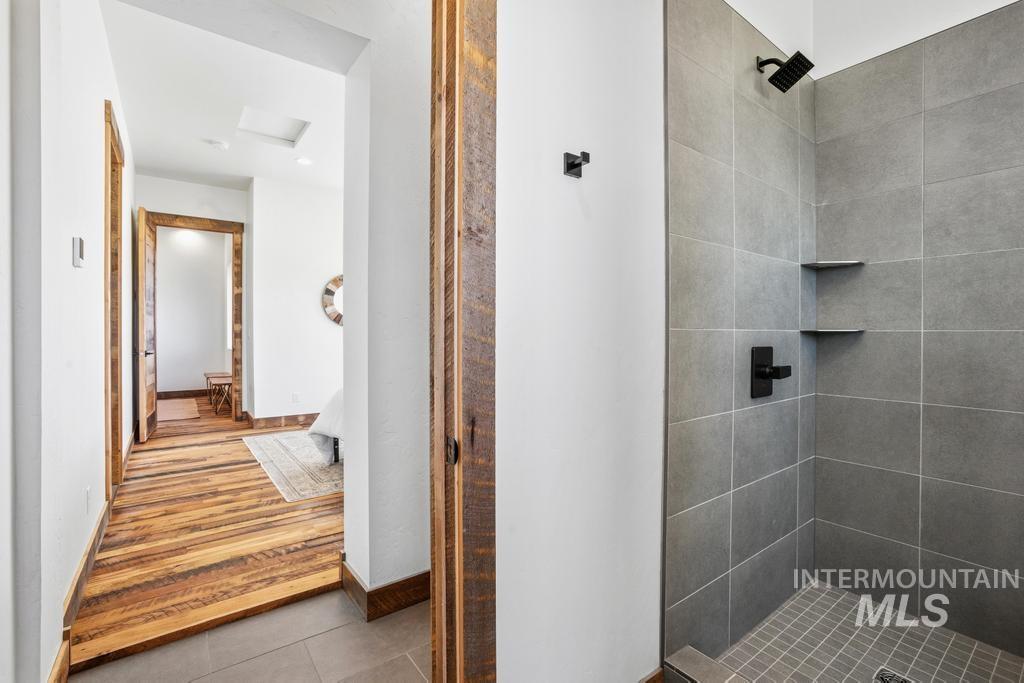 Walk-in shower featuring large format gray tile, matte black fixtures, and built-in corner shelving